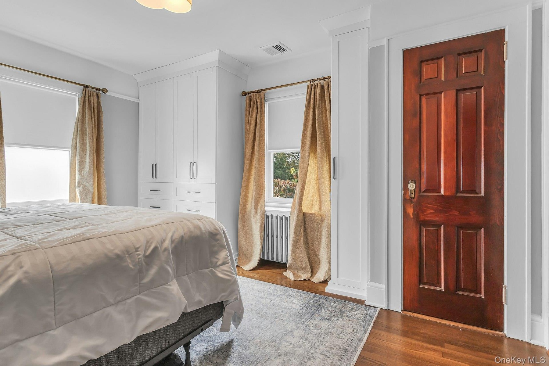 Hardwood flooring, built-in white cabinetry, custom window treatments, and a paneled wood door with decorative hardware