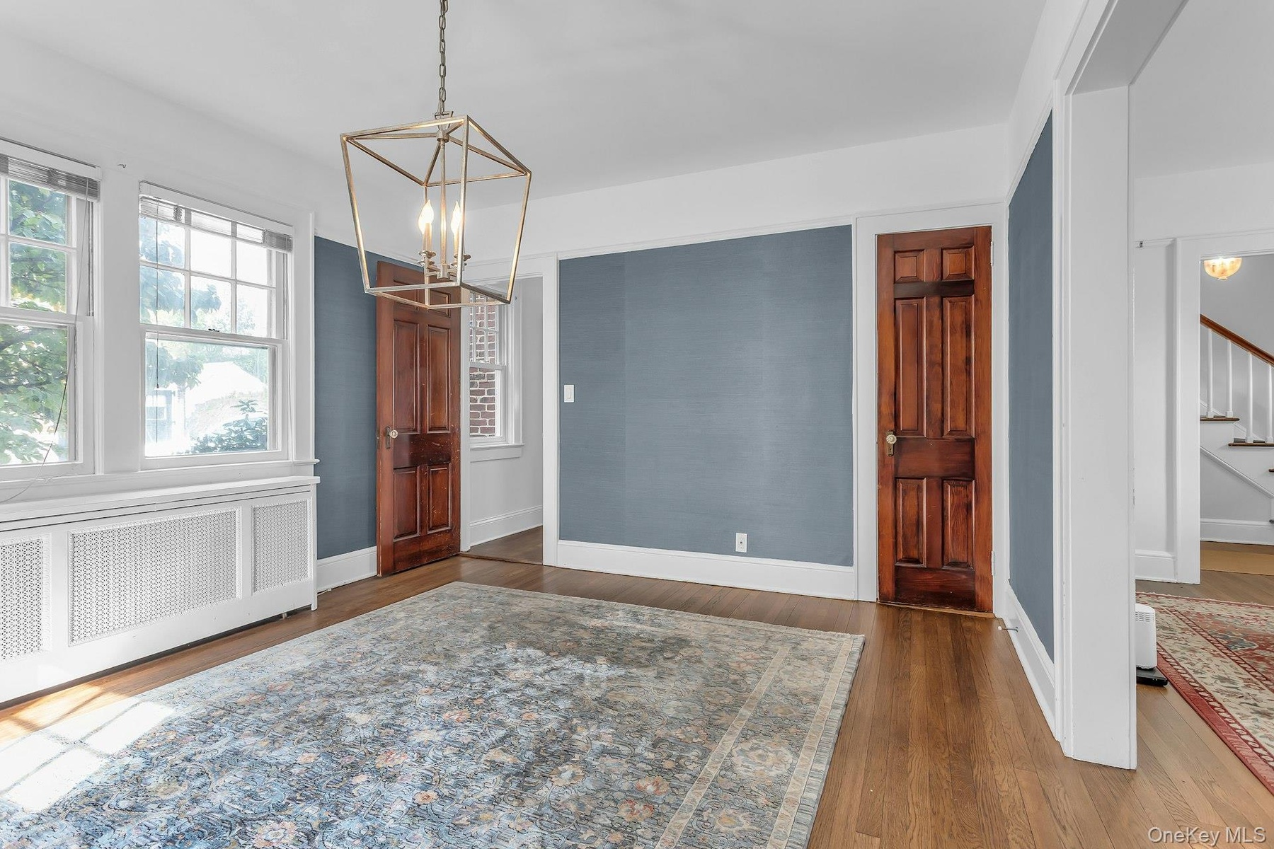 Hardwood flooring, painted walls, white trim, paneled doors, and a decorative ceiling light fixture