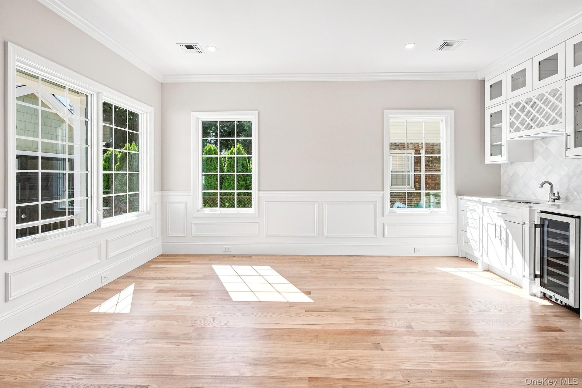 Dining Room - light wood-finish flooring, multiple paneled windows, recessed lighting, built-in cabinetry with glass inserts, and a beverage cooler.