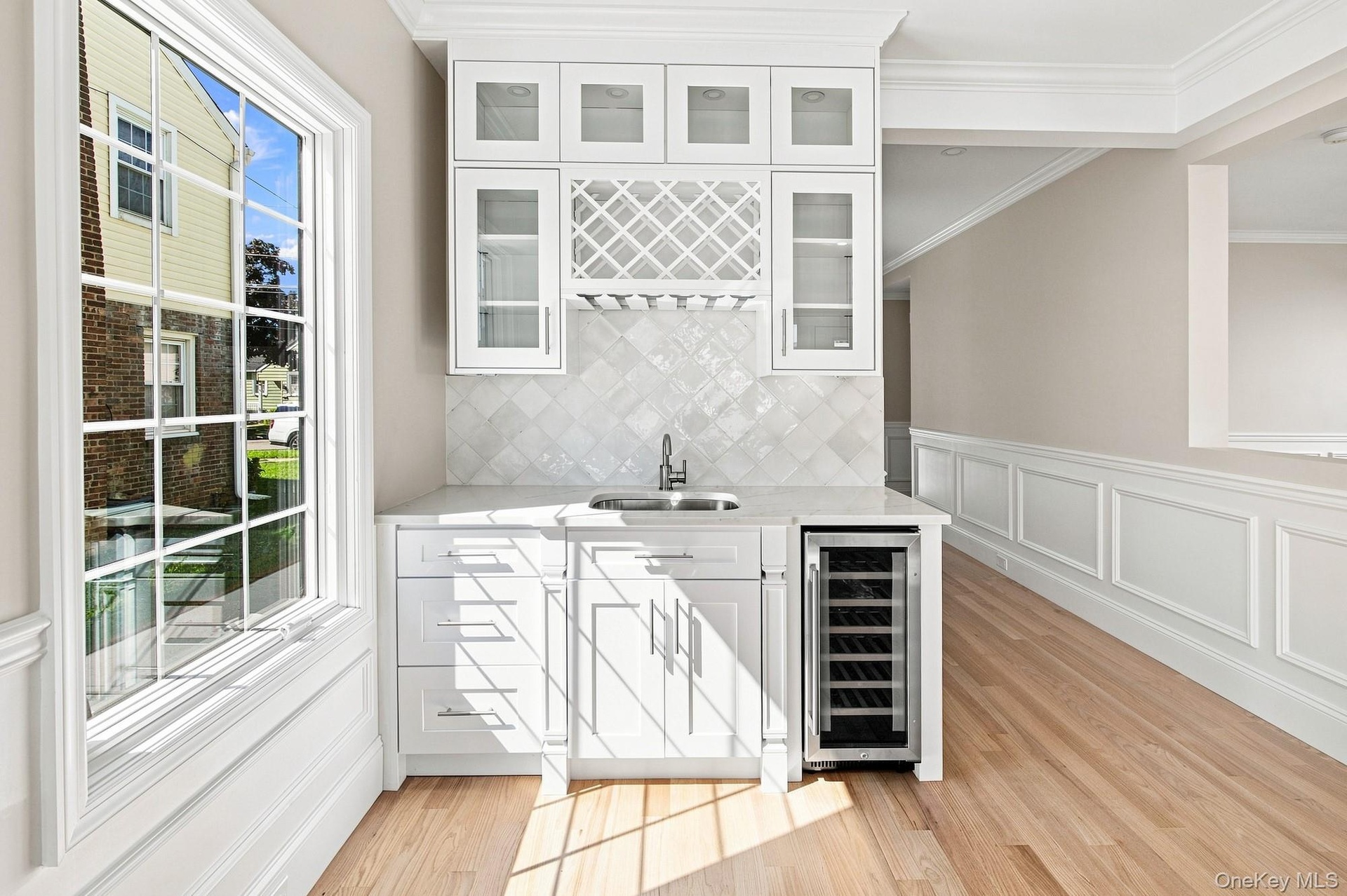 Built-in beverage station featuring white cabinetry, a wine rack, and a beverage cooler.