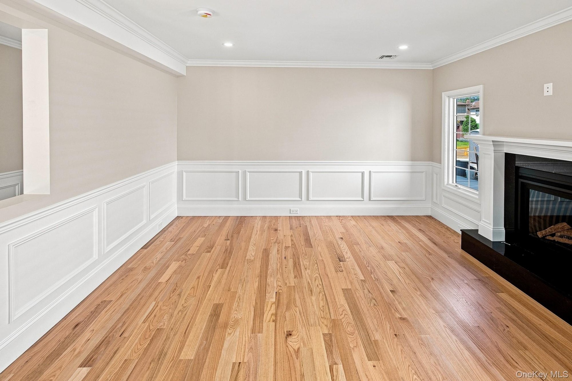 Family Room - hardwood flooring, crown molding, wainscoting, recessed lighting, and fireplace with a mantel.