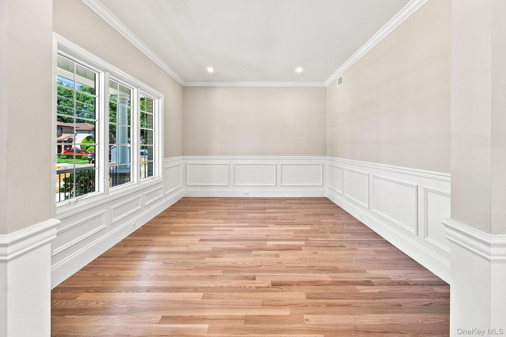 Flexible space: office, study, den, playroom. Wood-finish flooring, white paneled wainscoting, crown molding, recessed lighting, and multiple windows 