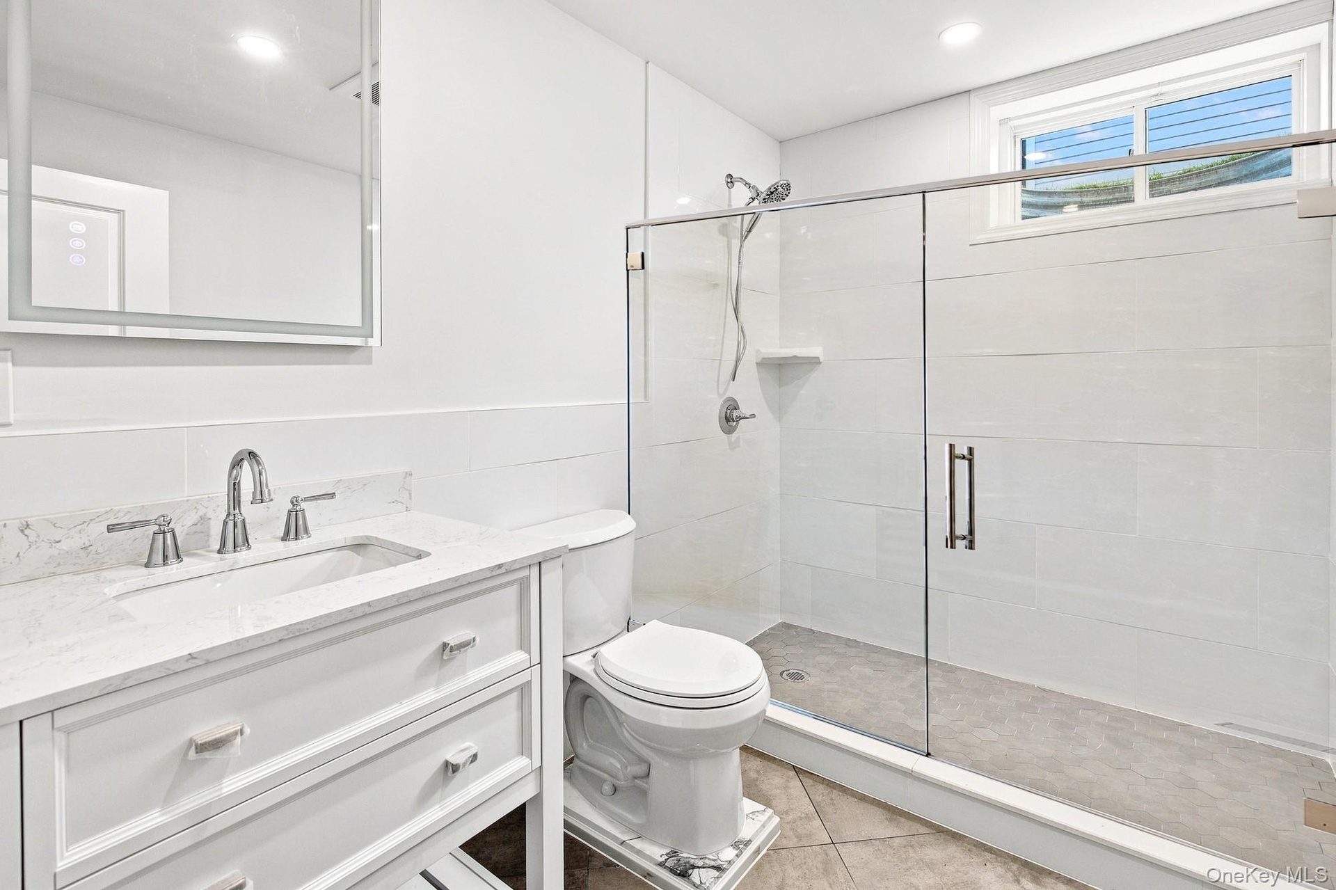 Lower level bath with white vanity with an integrated rectangular sink, chrome fixtures, and white countertop.
