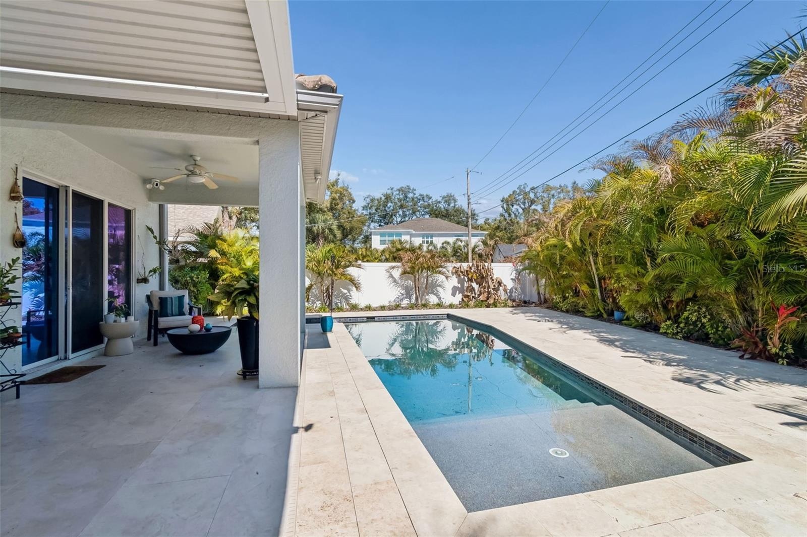 A poolside view toward the covered patio and the home’s open living area.