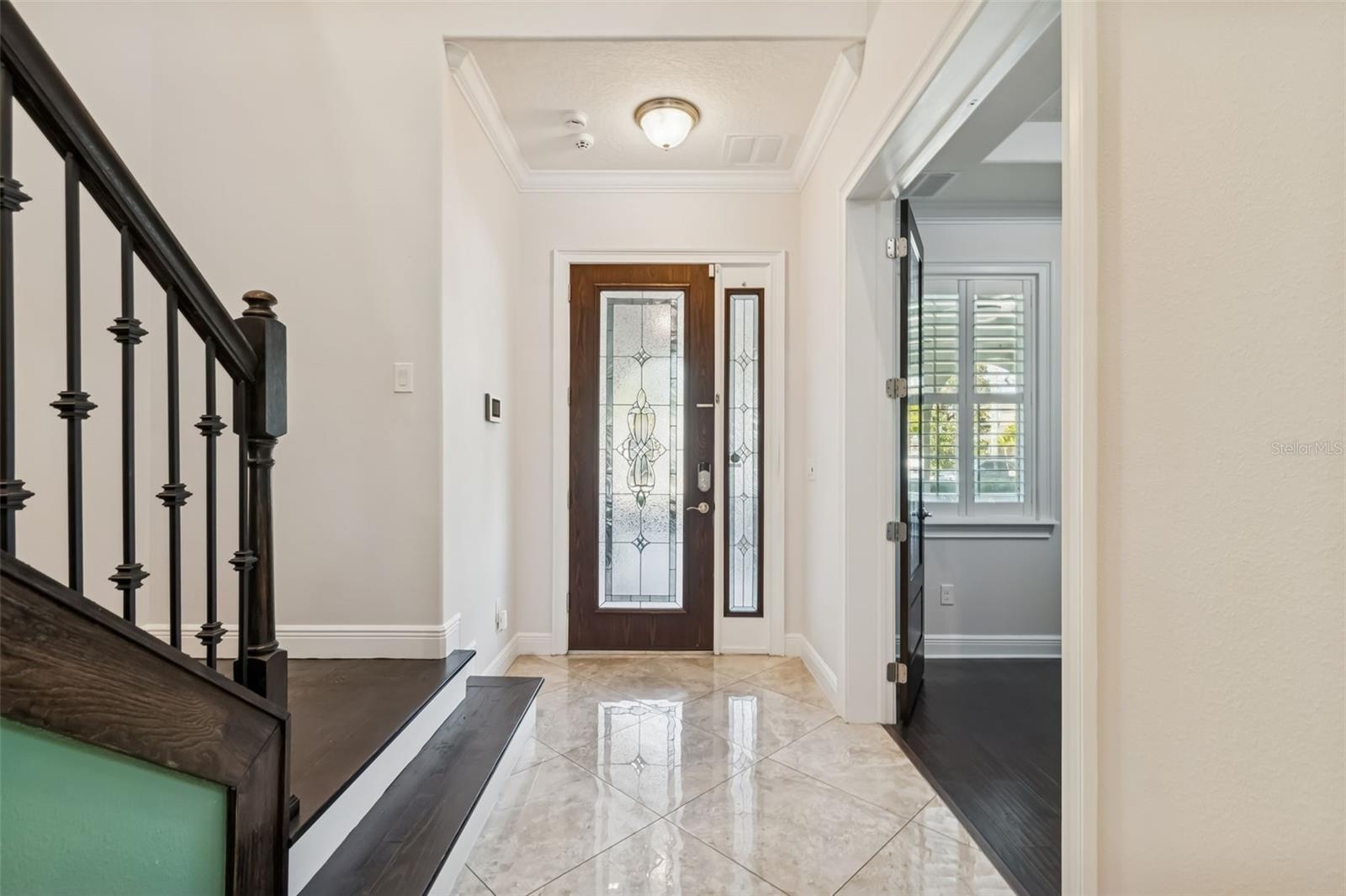 A welcoming foyer with decorative glass entry doors and natural light