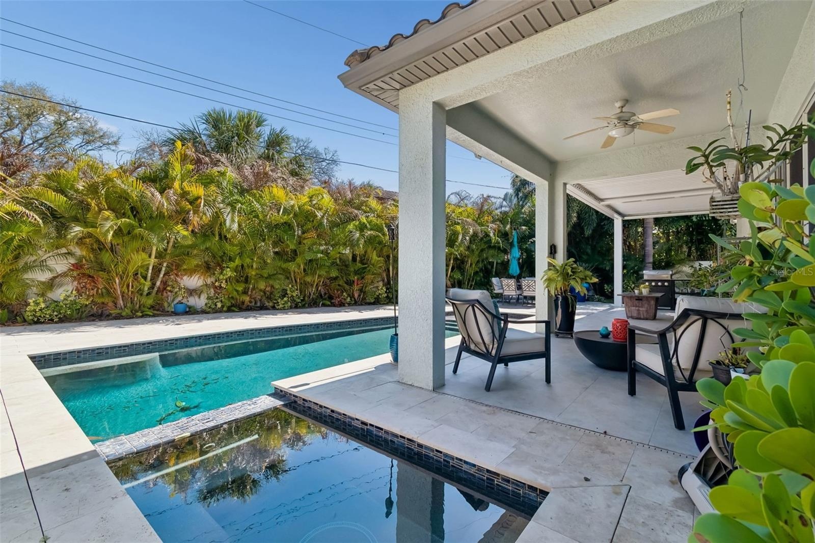 The heated pool, seen from its adjoining spa area, with the home and covered patio beyond.