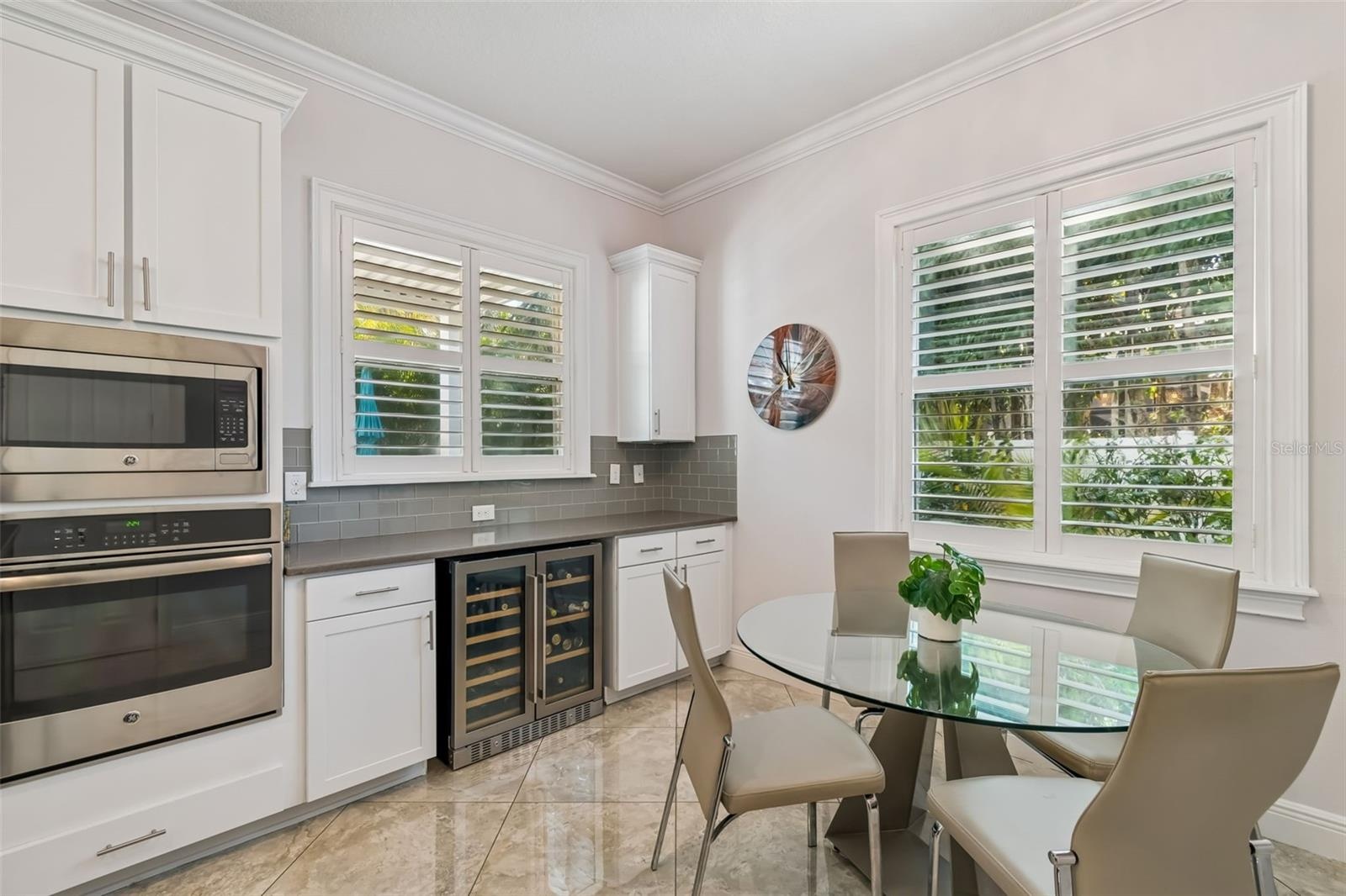 A bright kitchen corner featuring double ovens and a wine refrigerator