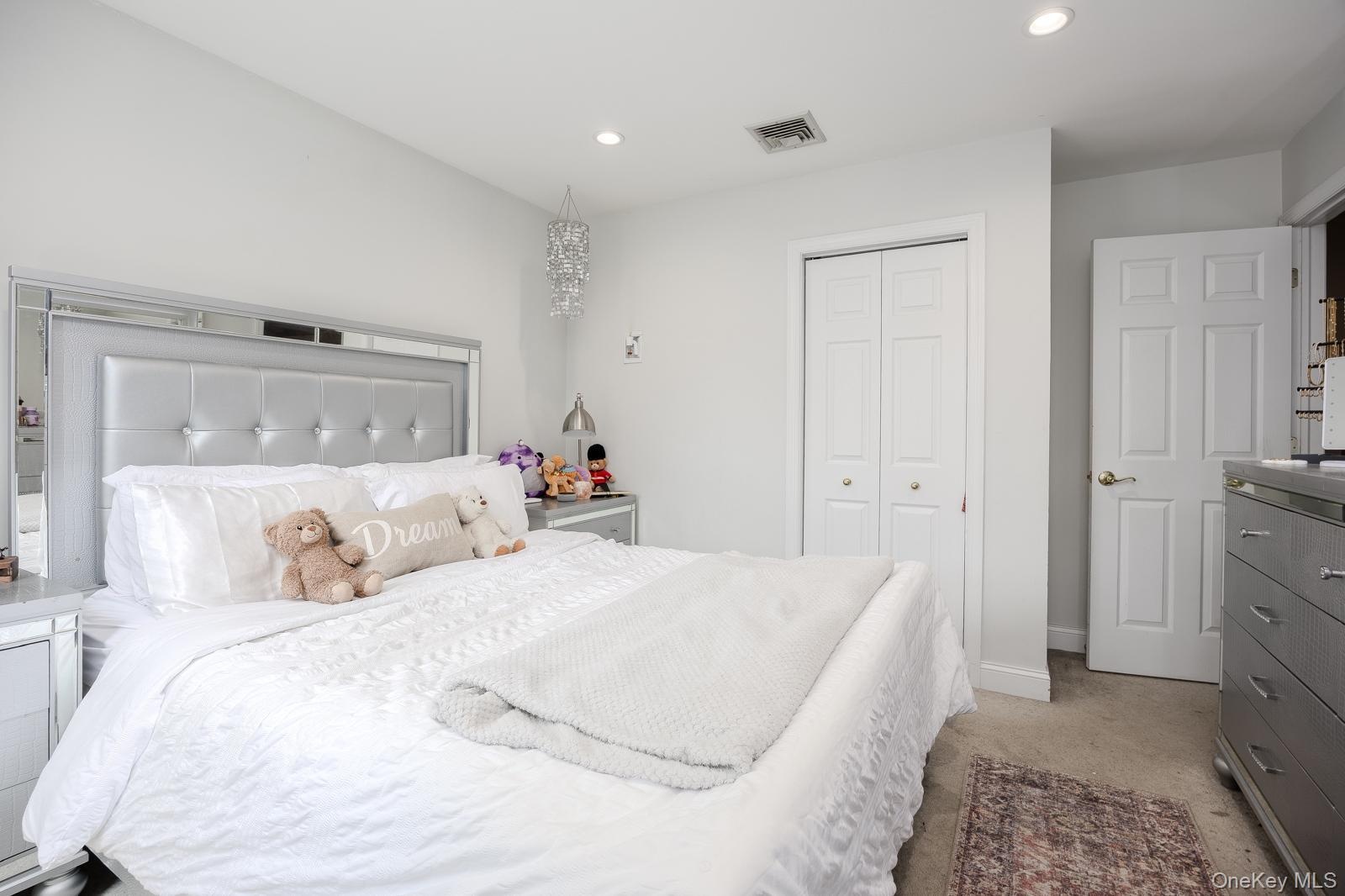 Recessed lighting, white bi-fold closet doors, white paneled door, and neutral-toned carpeting