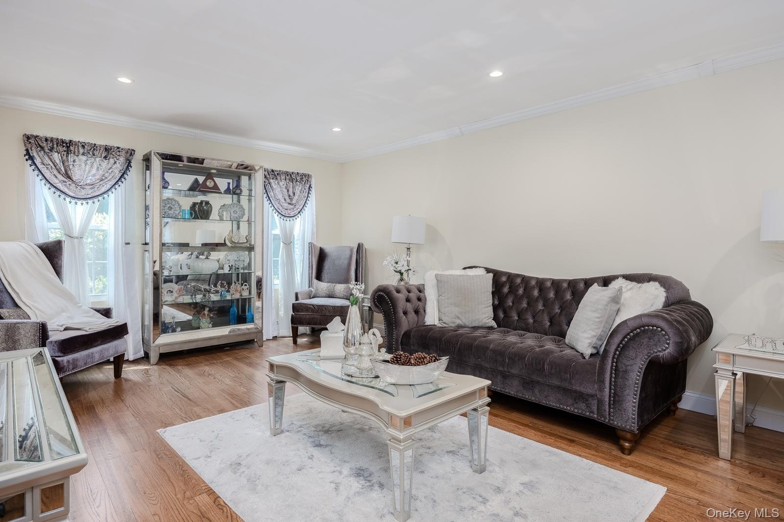 Recessed lighting, crown molding, wood-finish flooring, and white wall finishes