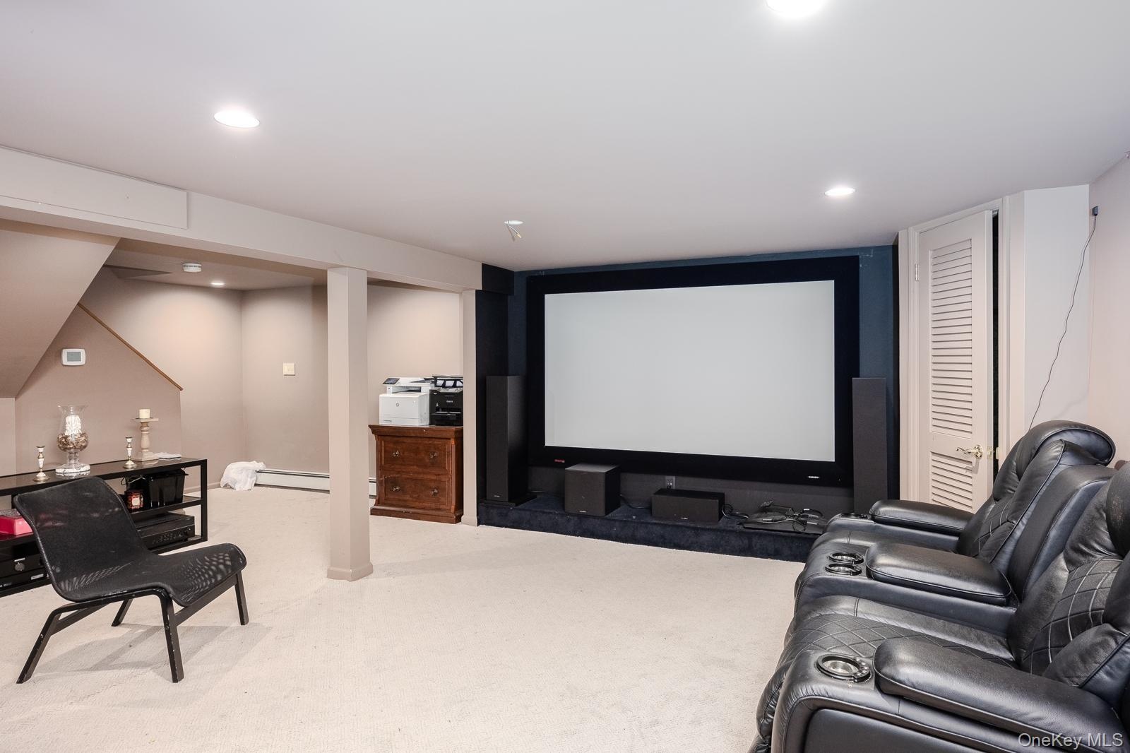 Entertainment area featuring a large projection screen, recessed lighting, and carpet flooring
