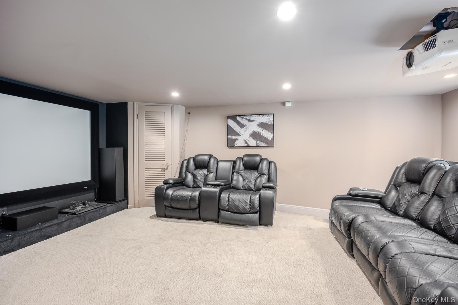 Media room featuring a large projection screen, projector, and recessed ceiling lighting