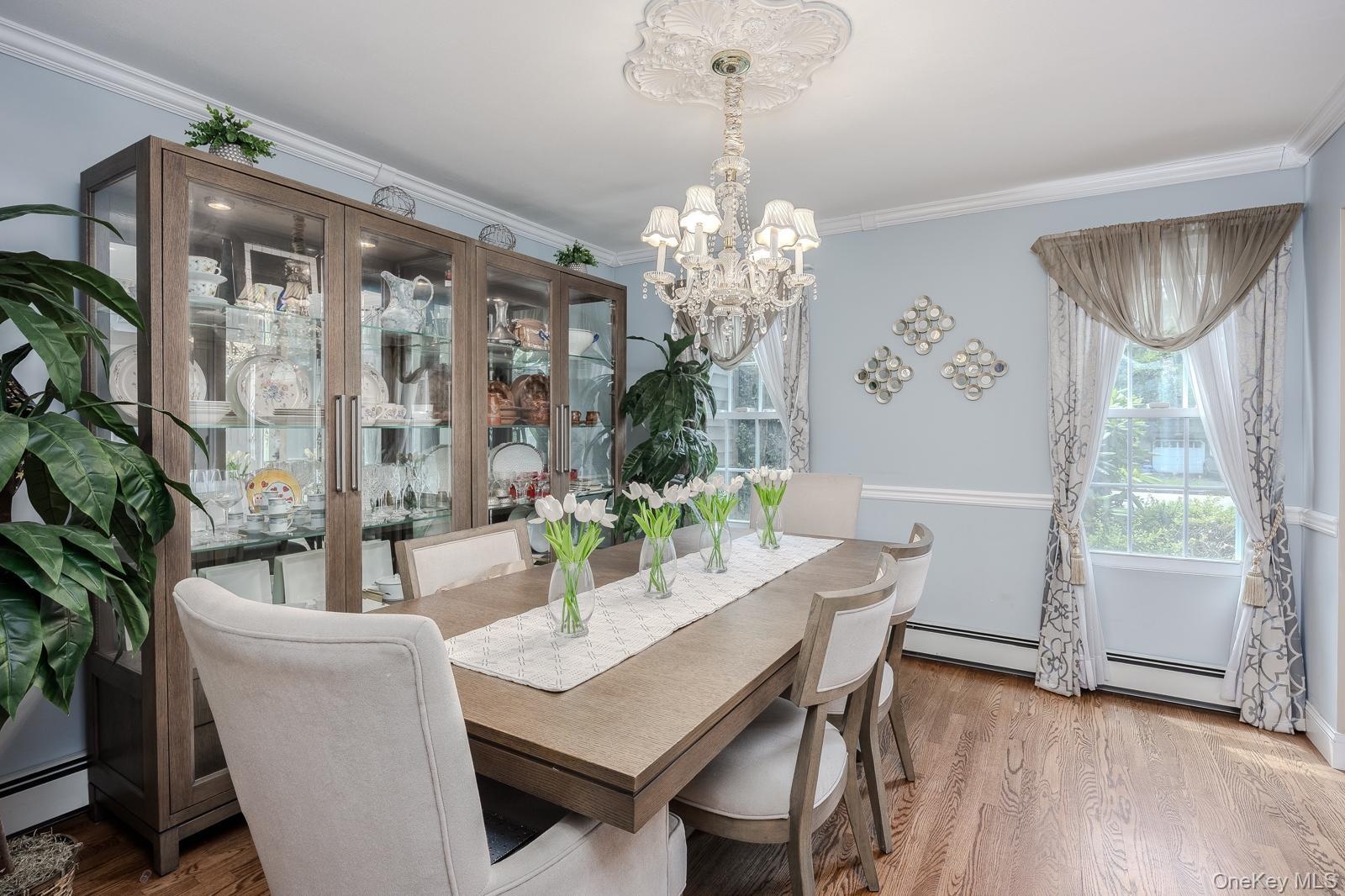 Formal Dining Room with hardwood flooring throughout, featuring crown molding, a decorative ceiling medallion, and an elaborate chandelier