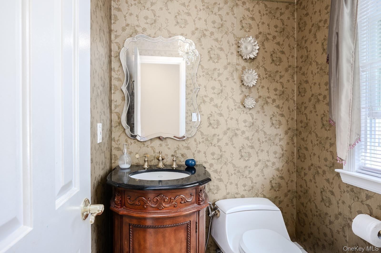 Half Bathroom ornate vanity with dark countertop, undermount sink, and decorative faucet