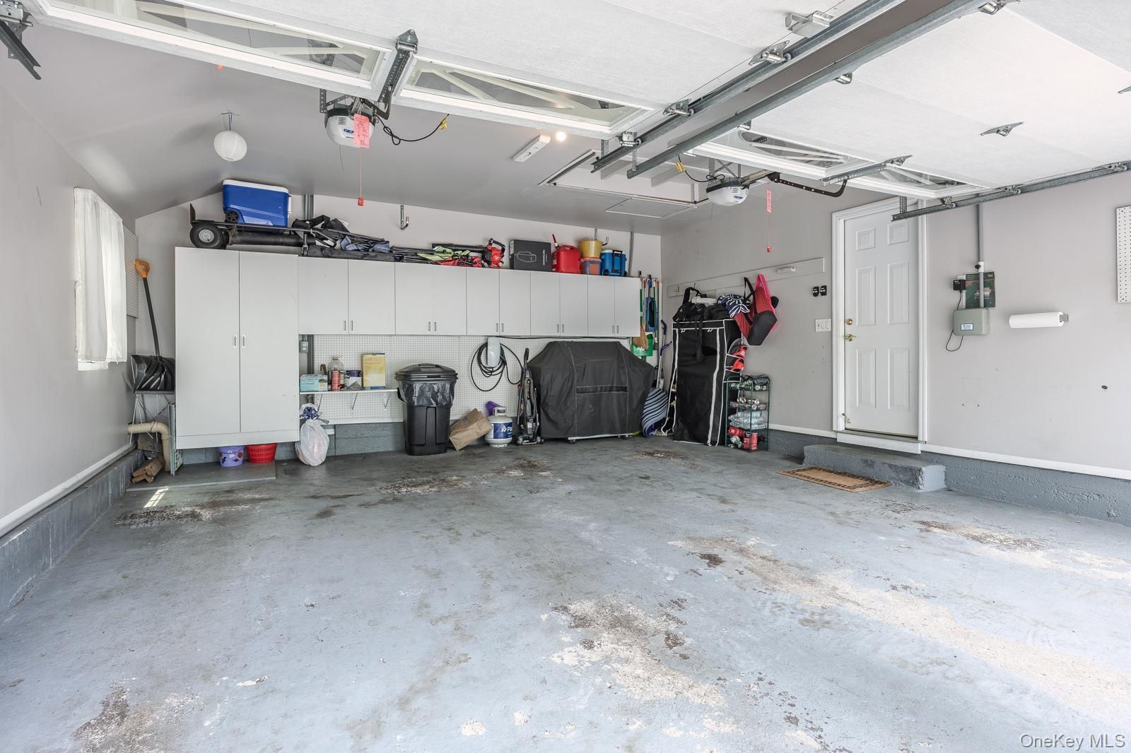 Attached garage featuring built-in cabinetry, overhead lighting, and a service door