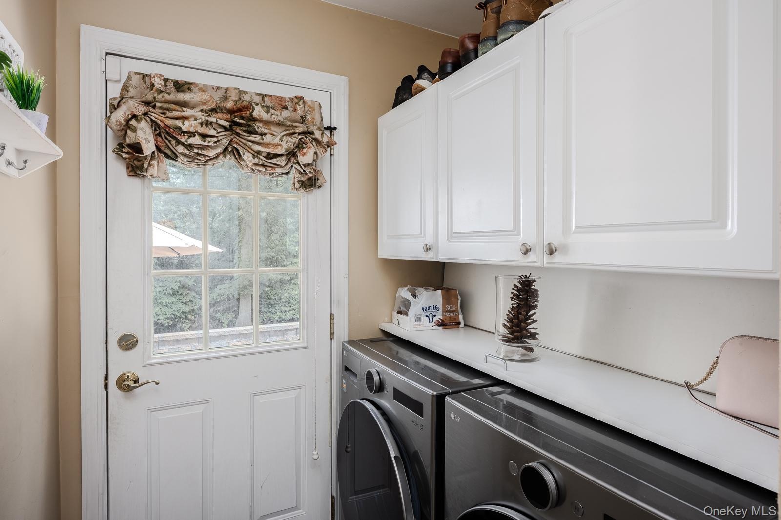 laundry room with white paneled door with window, overhead white cabinetry, and built-in countertop