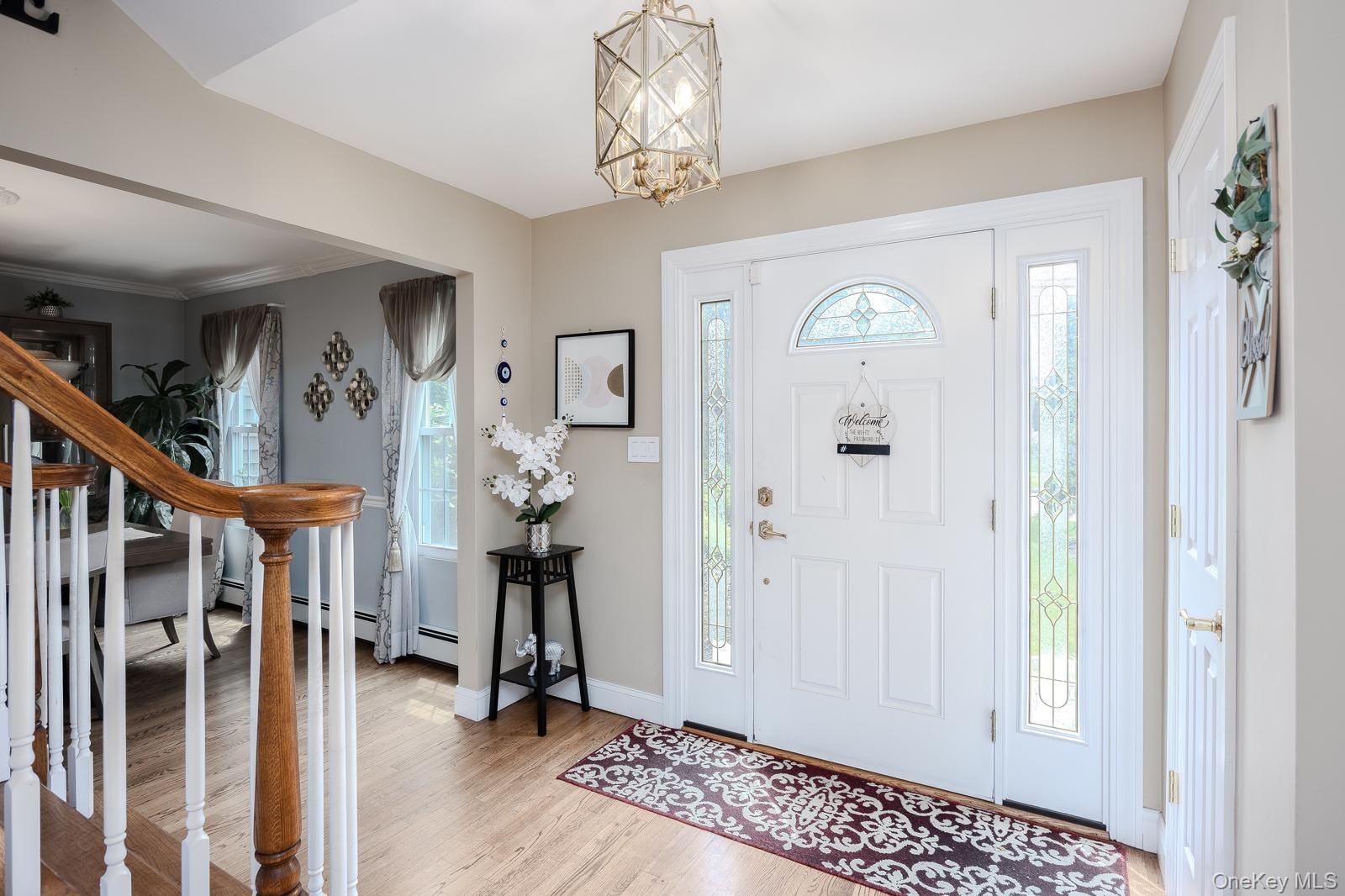 Foyer featuring a paneled entry door with an arched transom, sidelights with decorative glass, and wood-finish flooring