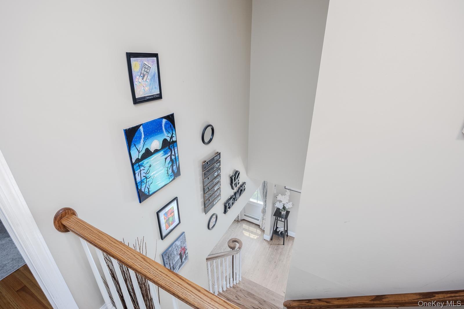 Two-story wall, wood-finish handrail, white painted risers, and wood-finish flooring