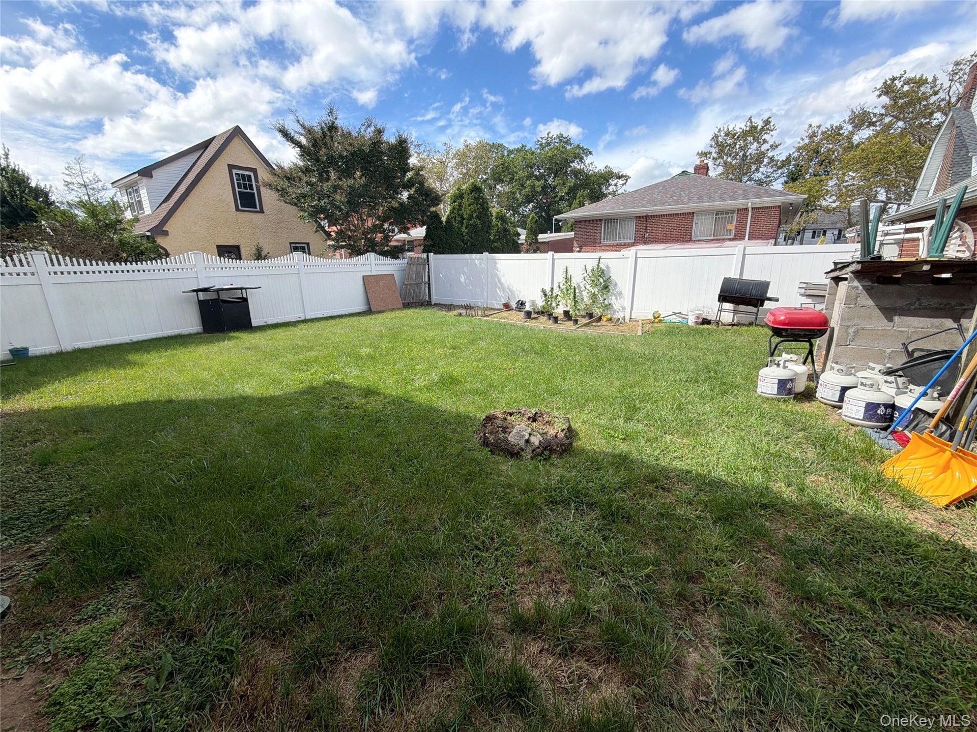 Expansive grassy yard with white privacy fencing