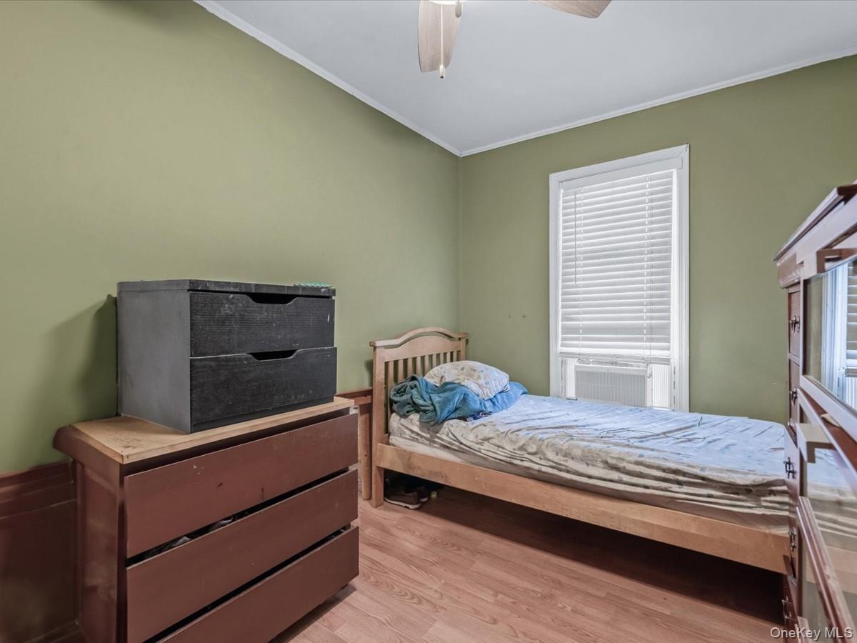Bedroom featuring light wood-style flooring, ornamental molding, and a ceiling fan