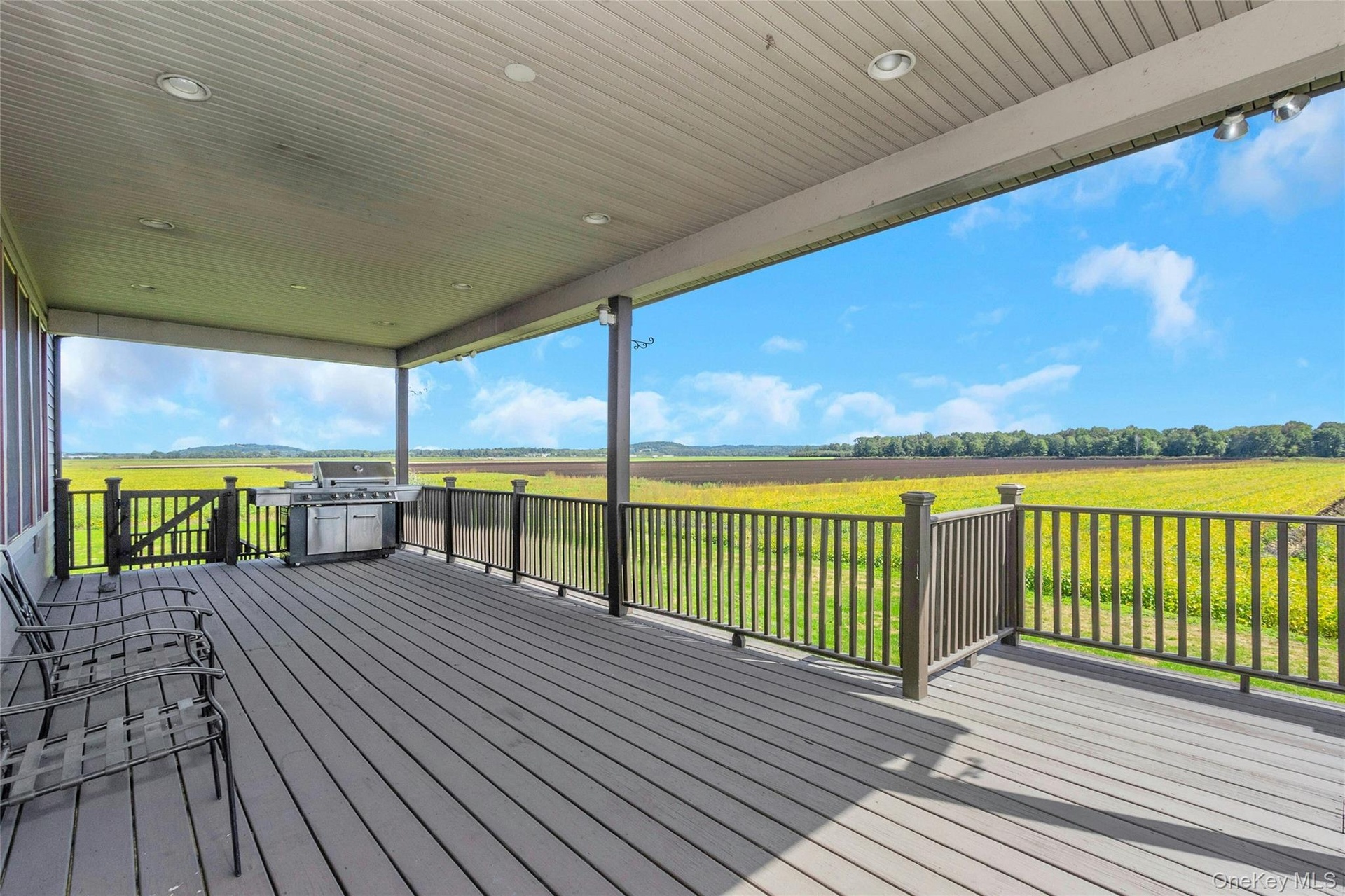 Spacious covered deck featuring composite decking, recessed lighting, and a dark-toned railing system
