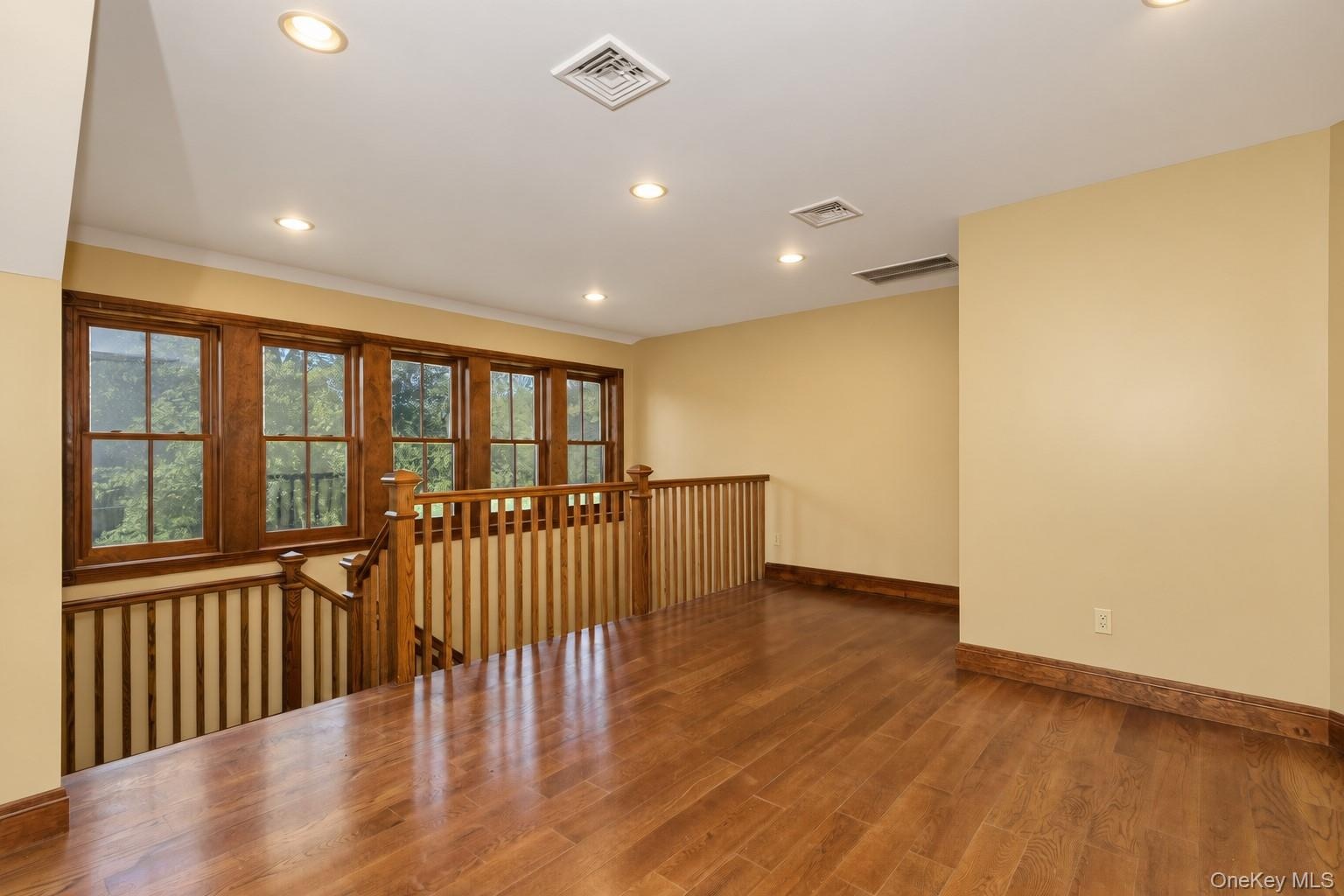 Hardwood flooring throughout, recessed lighting, wood-framed windows, and wood balusters