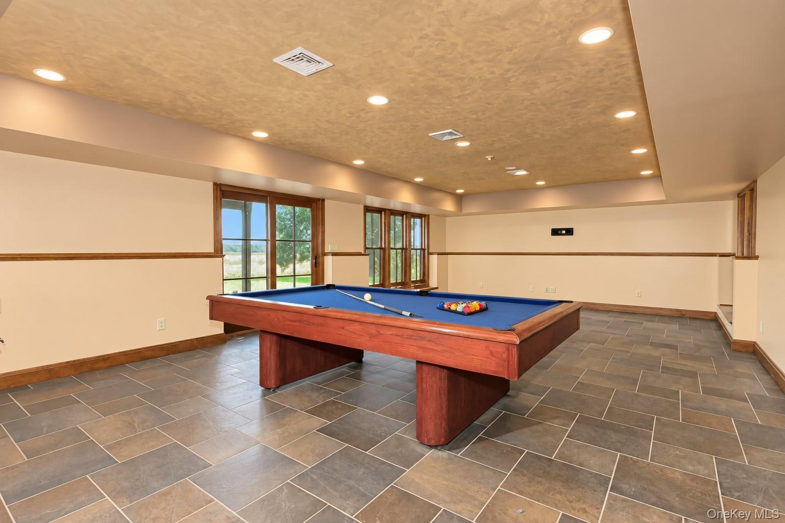 Recessed lighting illuminates the space, featuring tiled flooring, wood trim, and multiple glass-paned doors