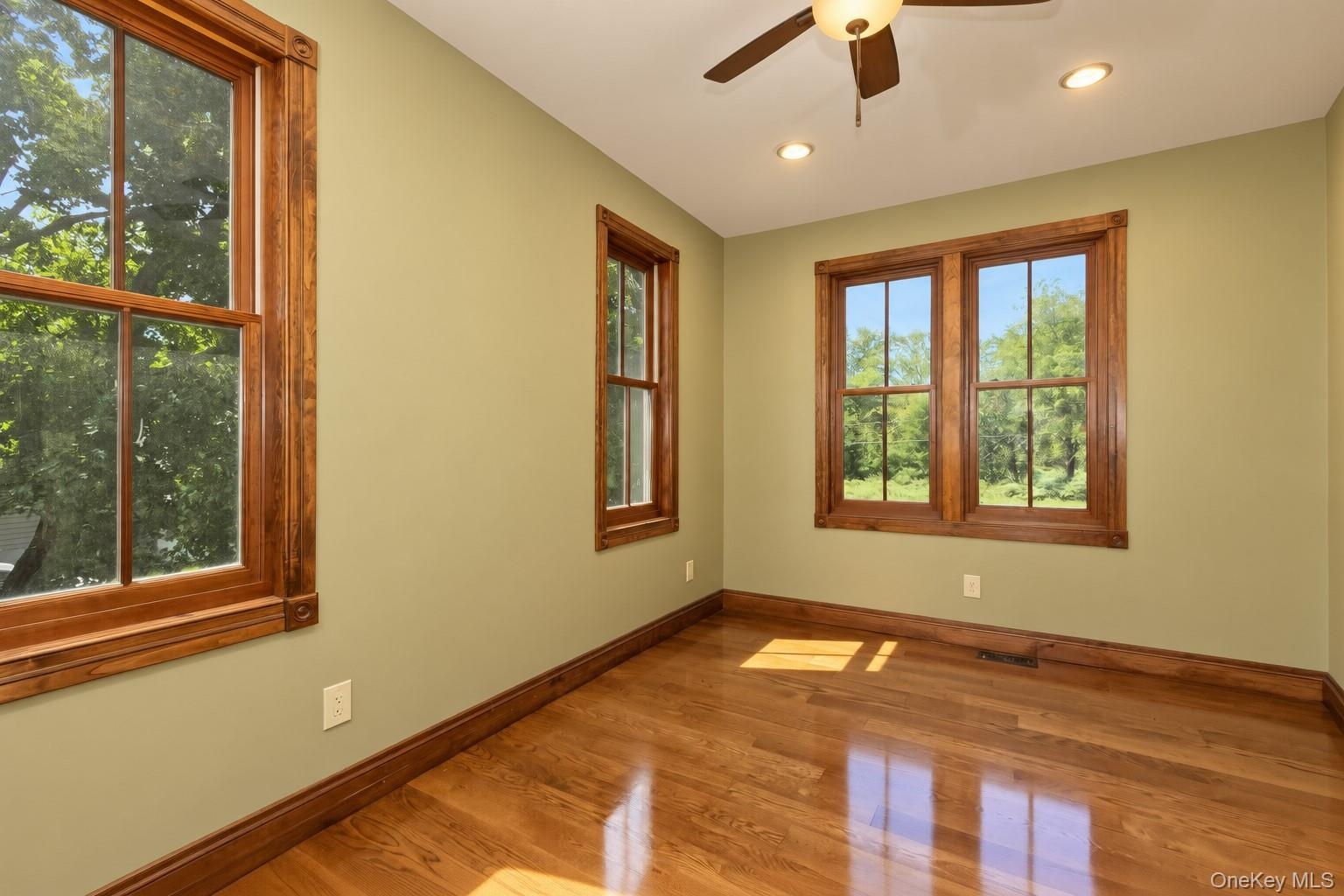 Hardwood flooring, wood-trimmed windows, recessed lighting, and a ceiling fan