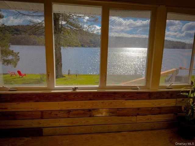 Expansive windows offering water frontage, wood-paneled interior walls, and a wood-finish floor