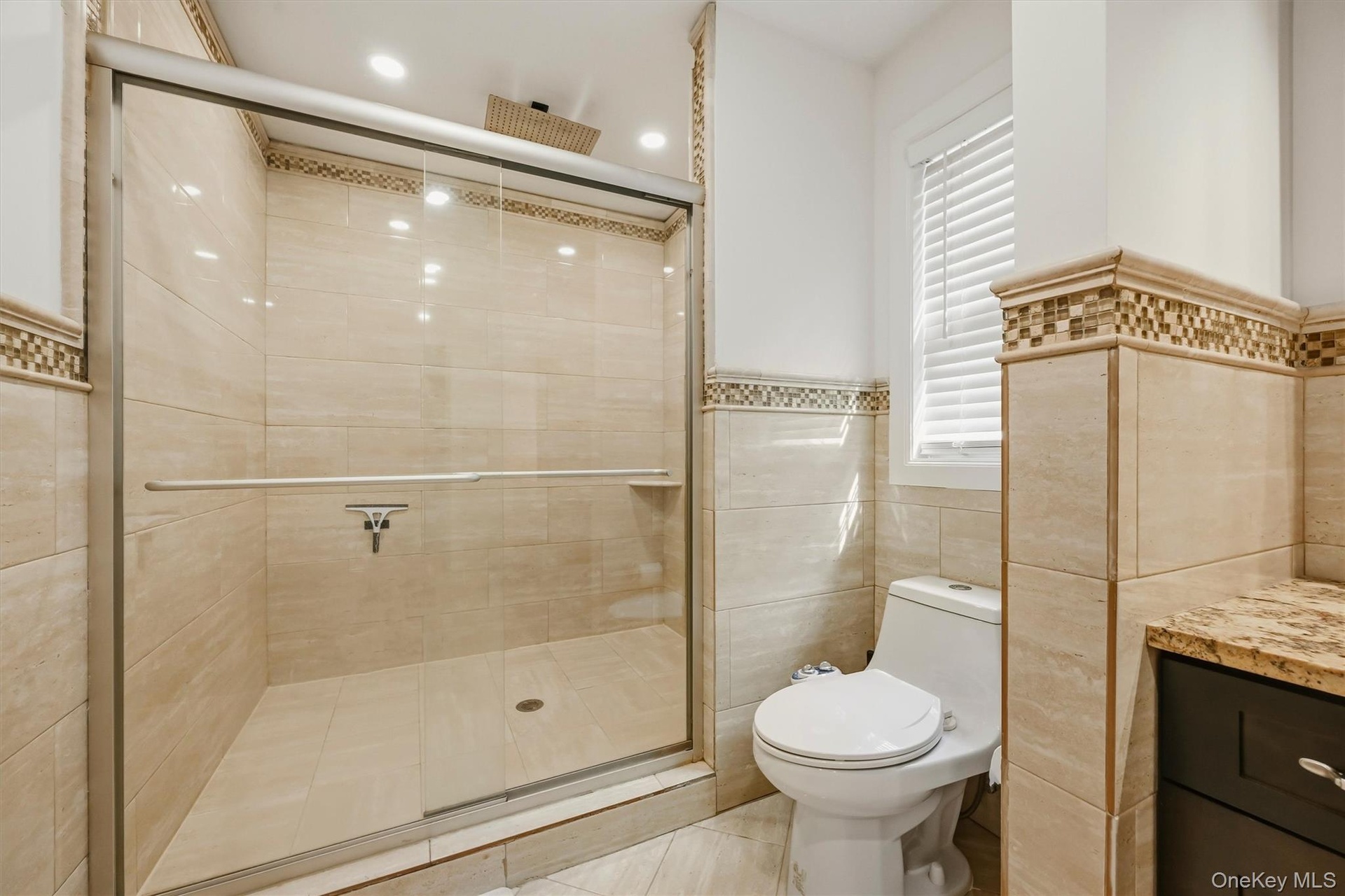 Primary bathroom shower with marble tile.