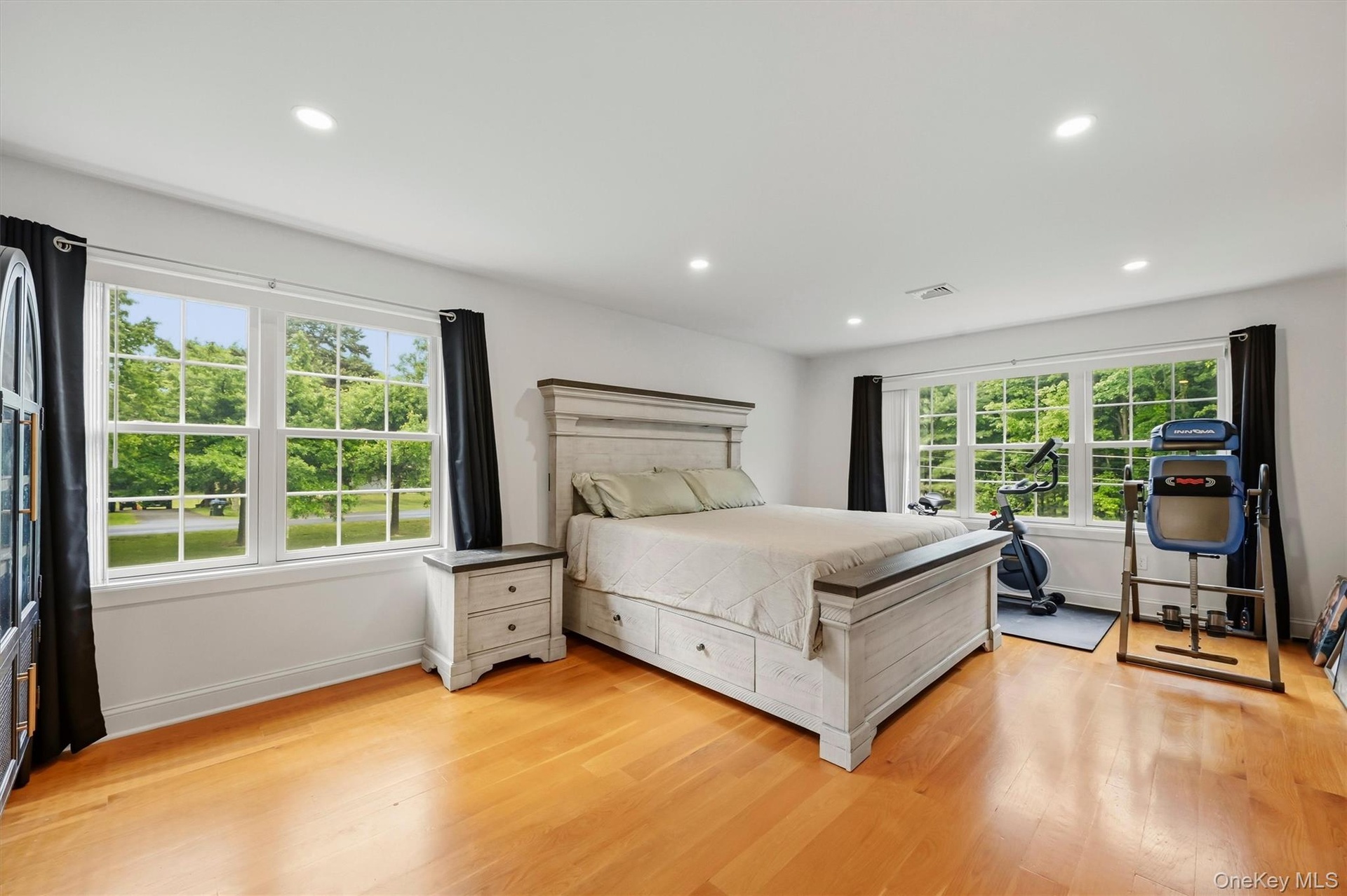 15x19 Primary Bedroom with recessed lighting, wide oak flooring and balcony access.