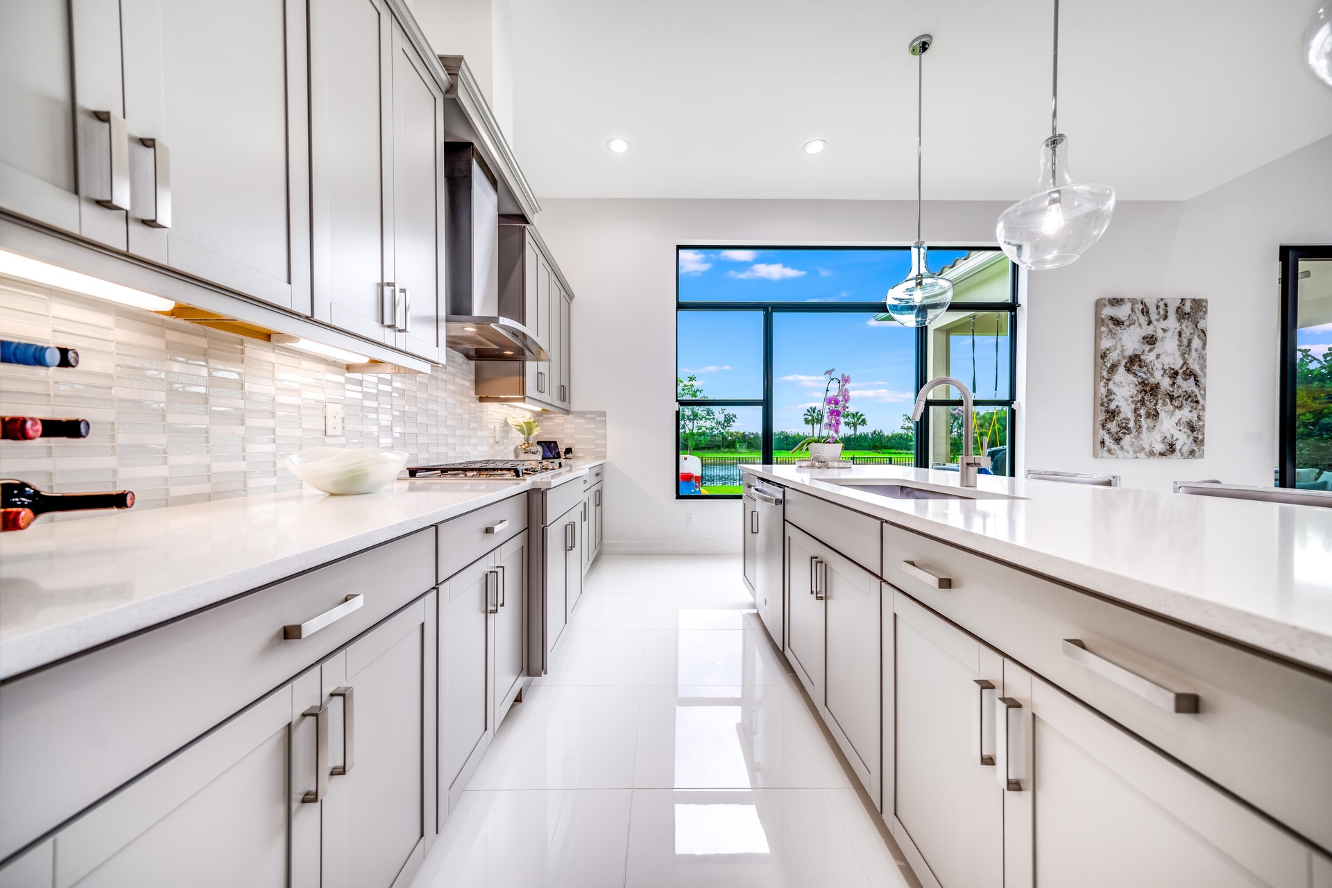 Modern kitchen featuring gray cabinetry, light countertops, a tile backsplash, and a large window