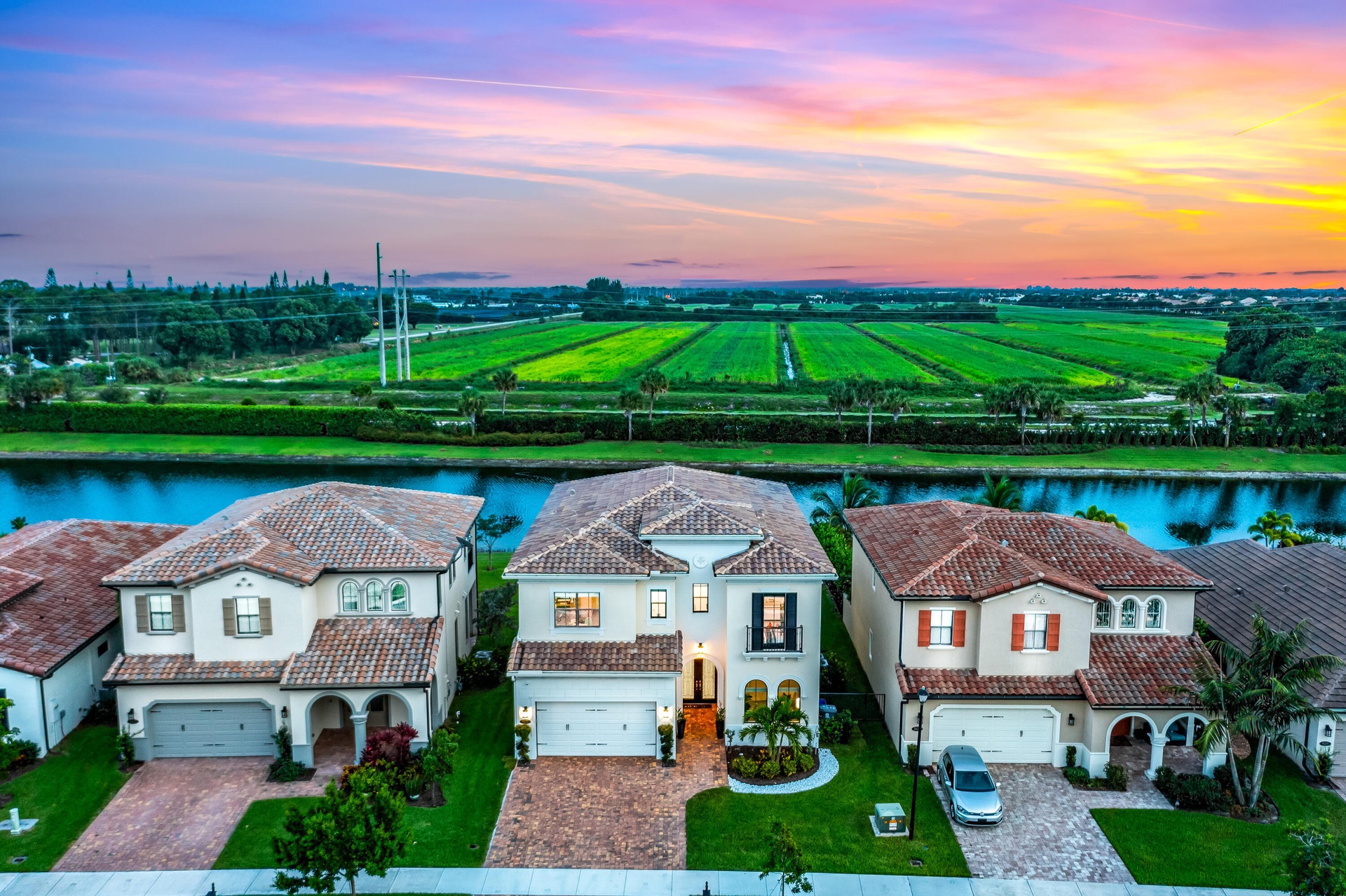 Waterfront property featuring tile roofs, stucco exteriors, and a manicured lawn