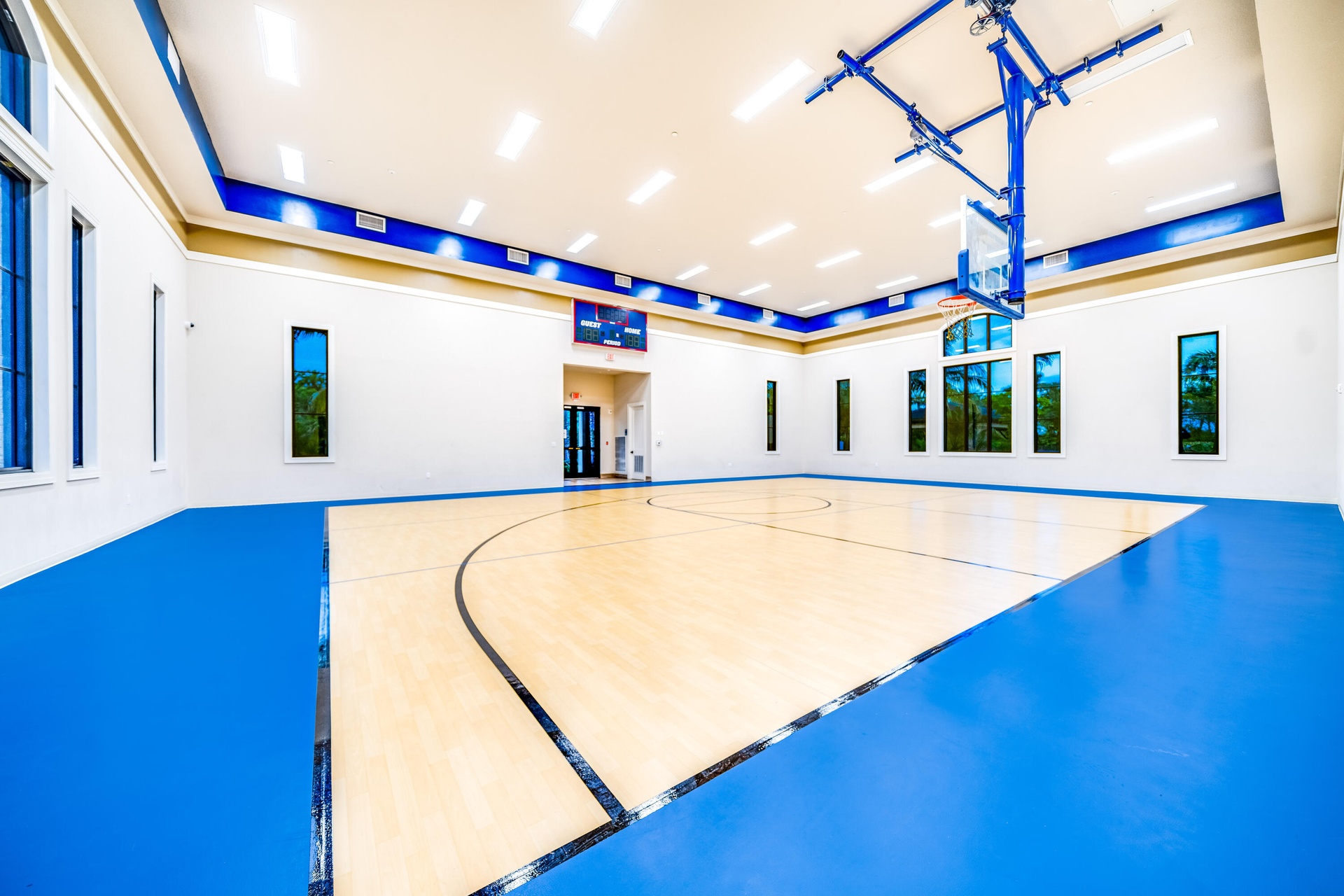Indoor court with a polished wood-finish playing surface, blue-finished perimeter, and high ceilings