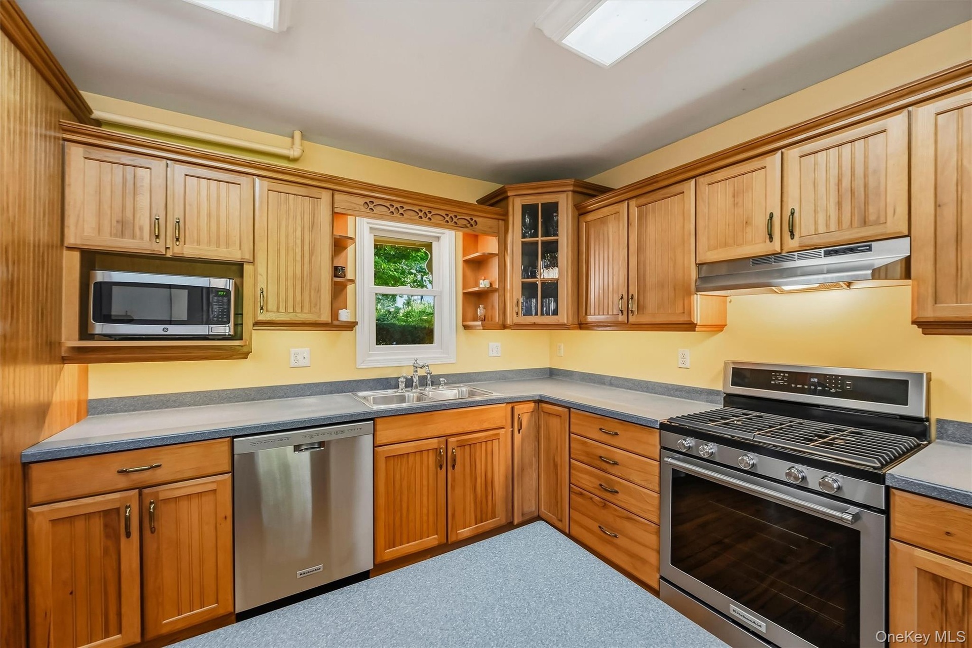 Wood-finish cabinetry with display cabinet, stainless steel appliances, and a built-in microwave