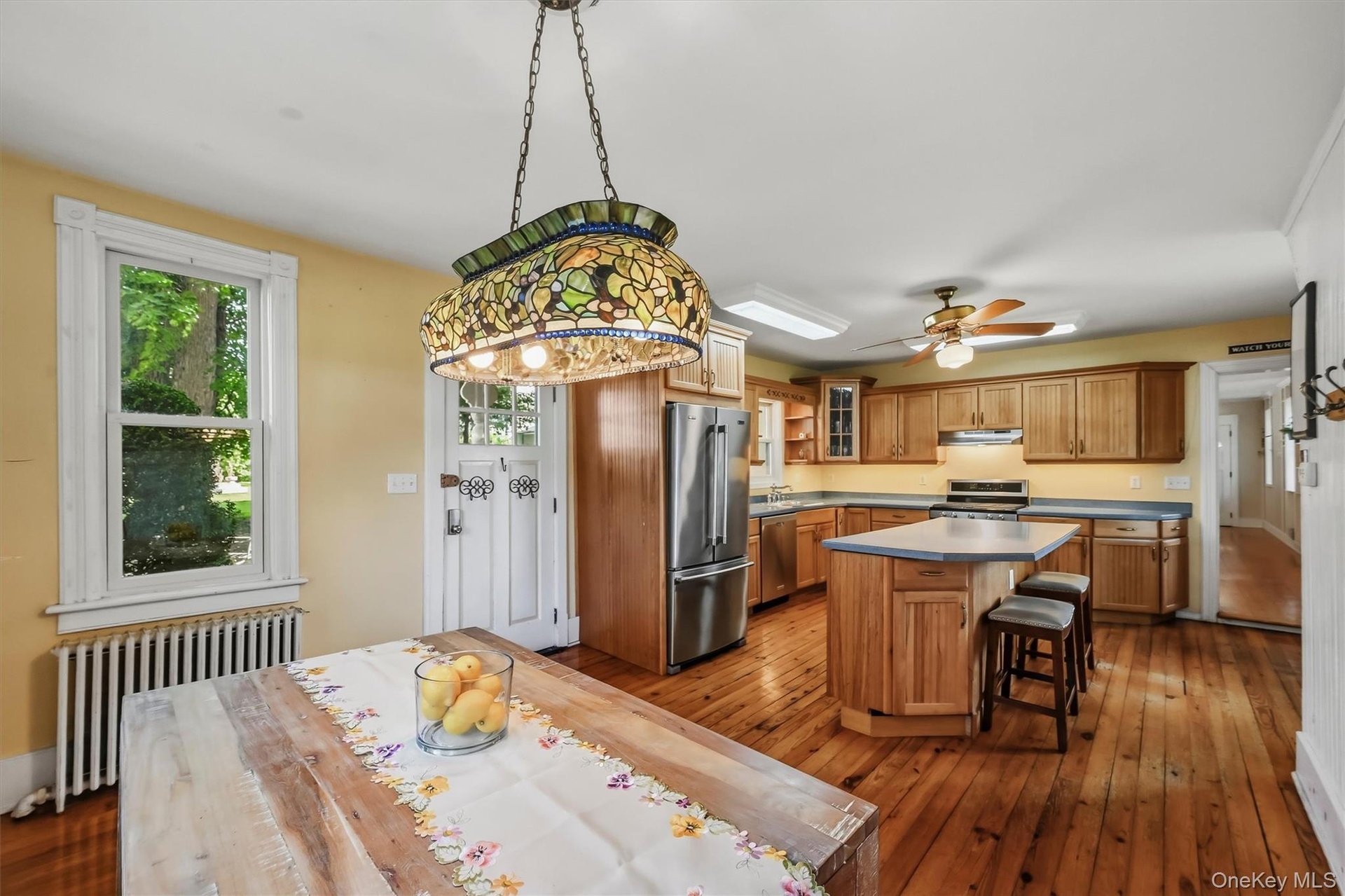 Open kitchen and dining area with center island, wood cabinetry, hardwood floors, and ample natural light