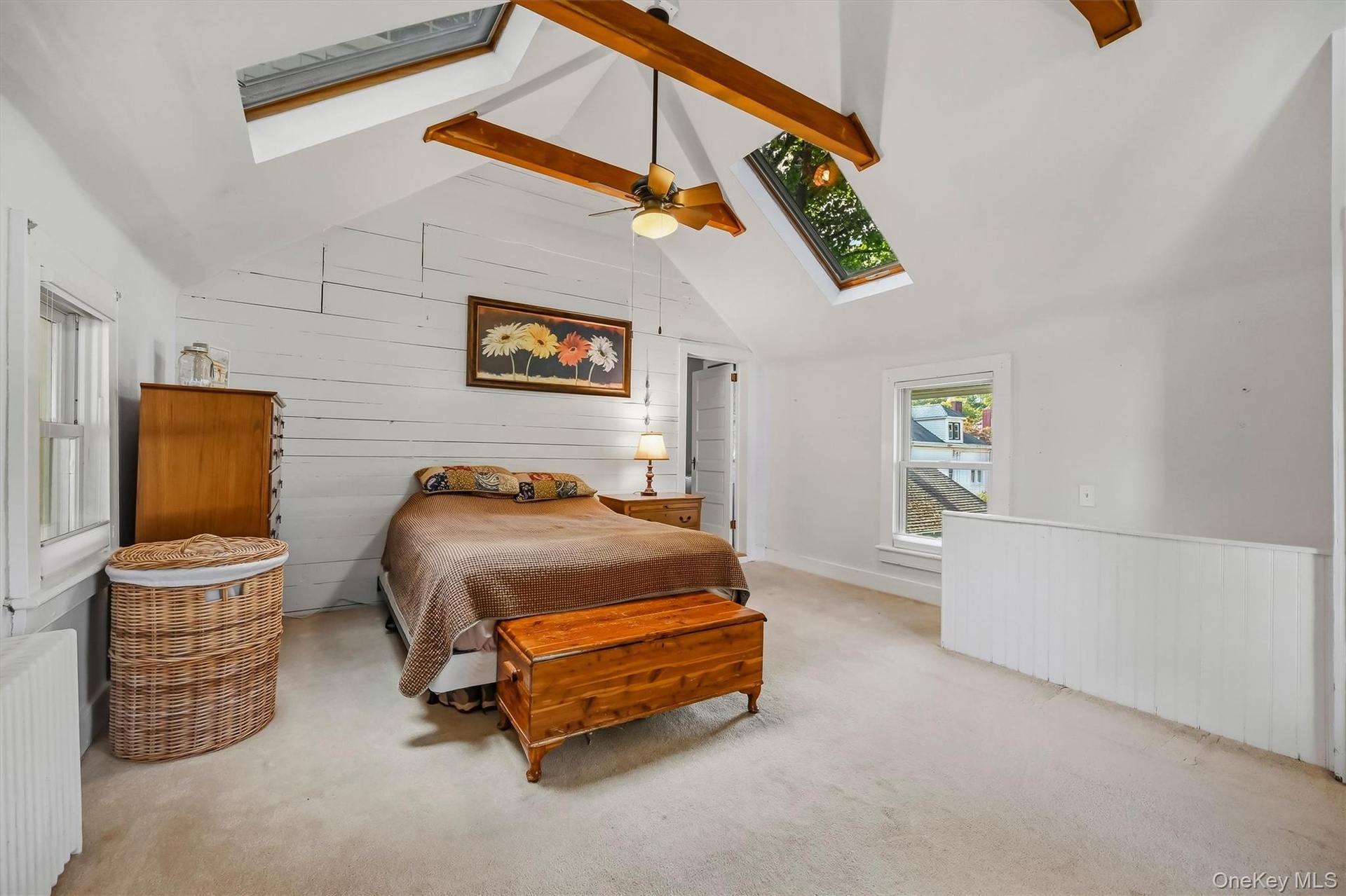 Another view highlighting the vaulted ceiling, skylights, exposed beams, and open layout