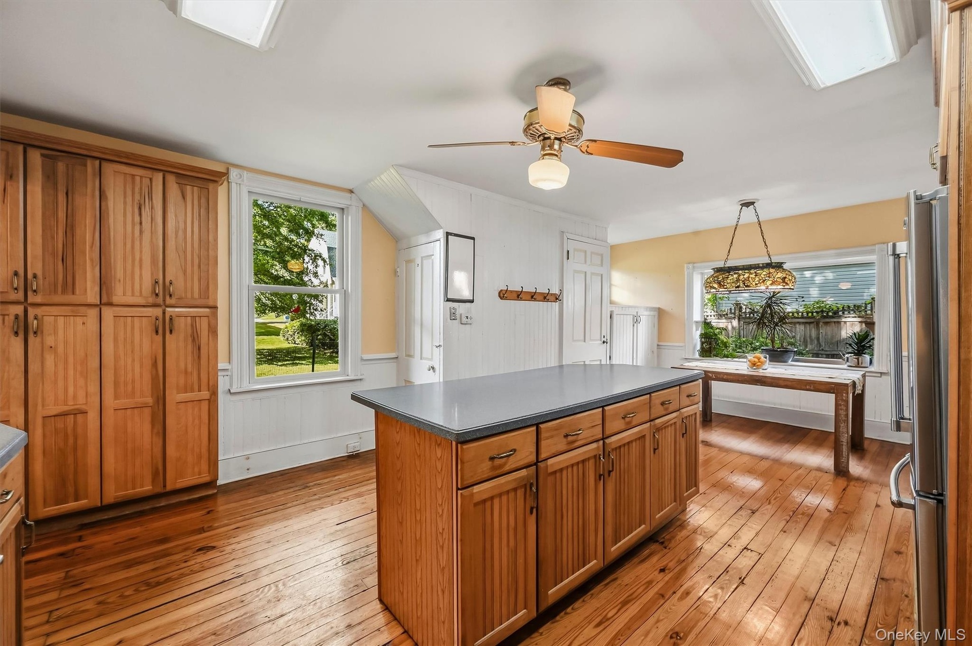 Spacious kitchen with center island, wood cabinetry, hardwood floors, and plenty of natural light