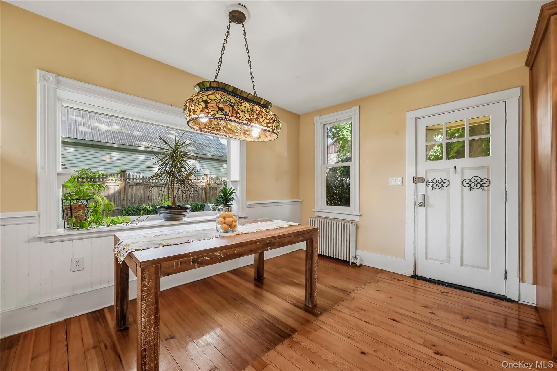 Bright dining area with hardwood floors, large picture window, and convenient exterior access