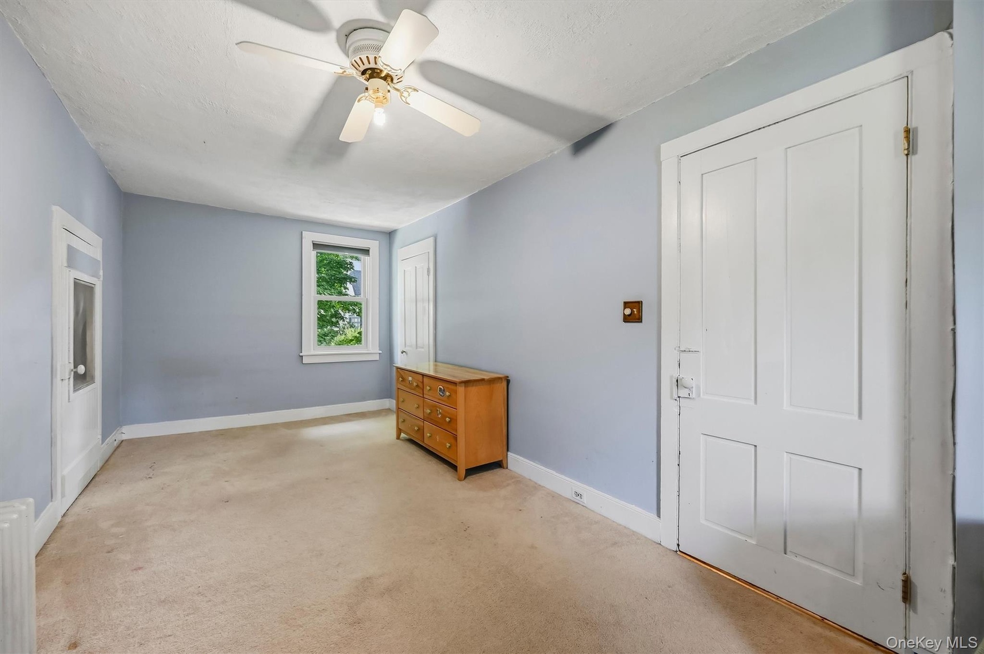 Spacious bedroom with ceiling fan, natural light, and ample closet space.