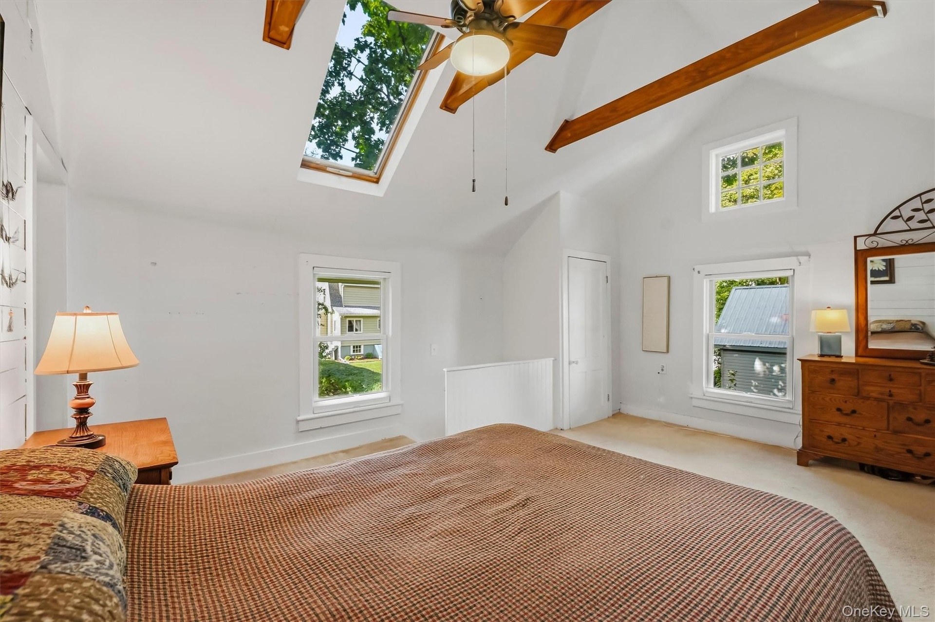 Bright primary bedroom with multiple windows and distinctive vaulted ceiling