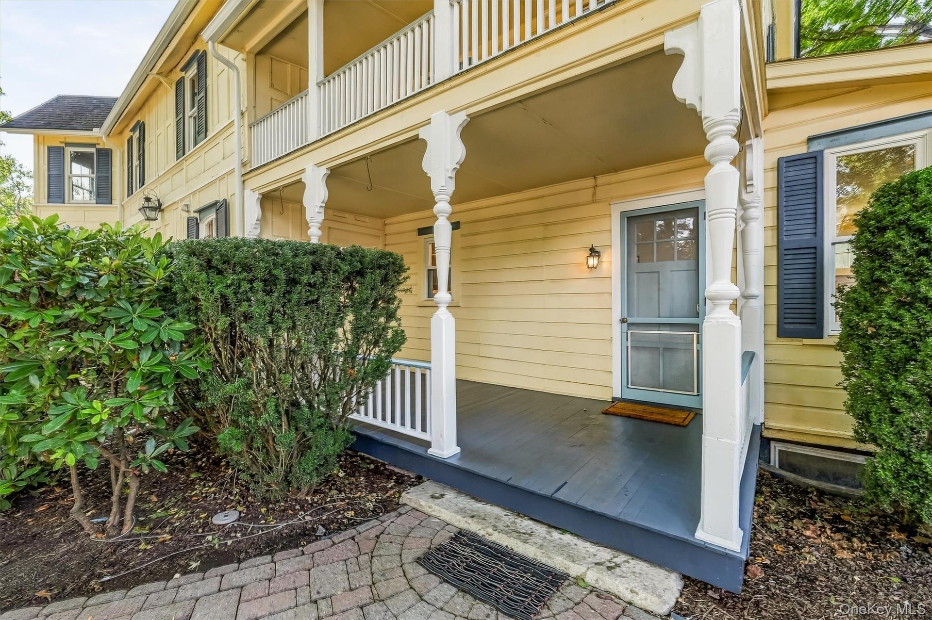 Welcoming covered porch with decorative columns and brick walkway
