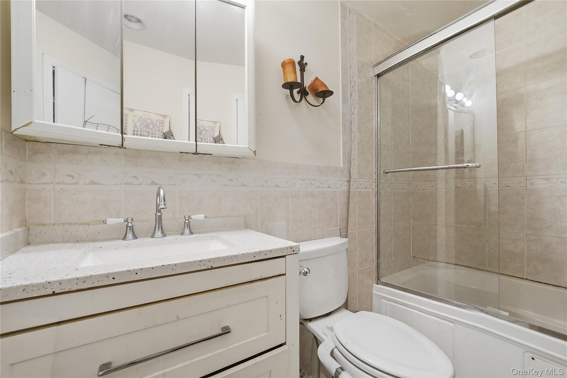 Unit 2 - Bathroom with bathtub and glass enclosure. Digitally decluttered.