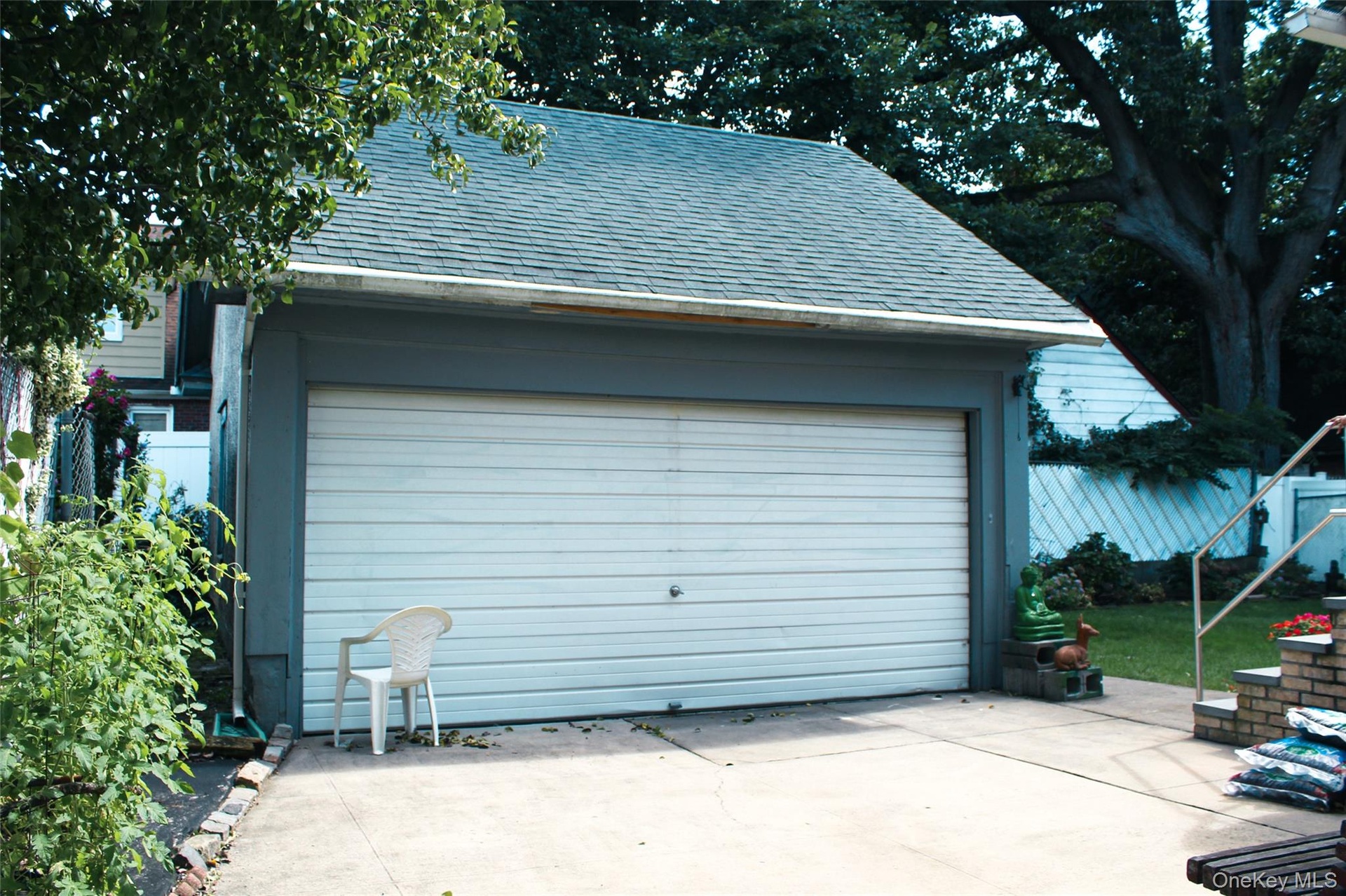 Detached  remote opening garage with a double vehicle door, asphalt shingle roof, and concrete driveway