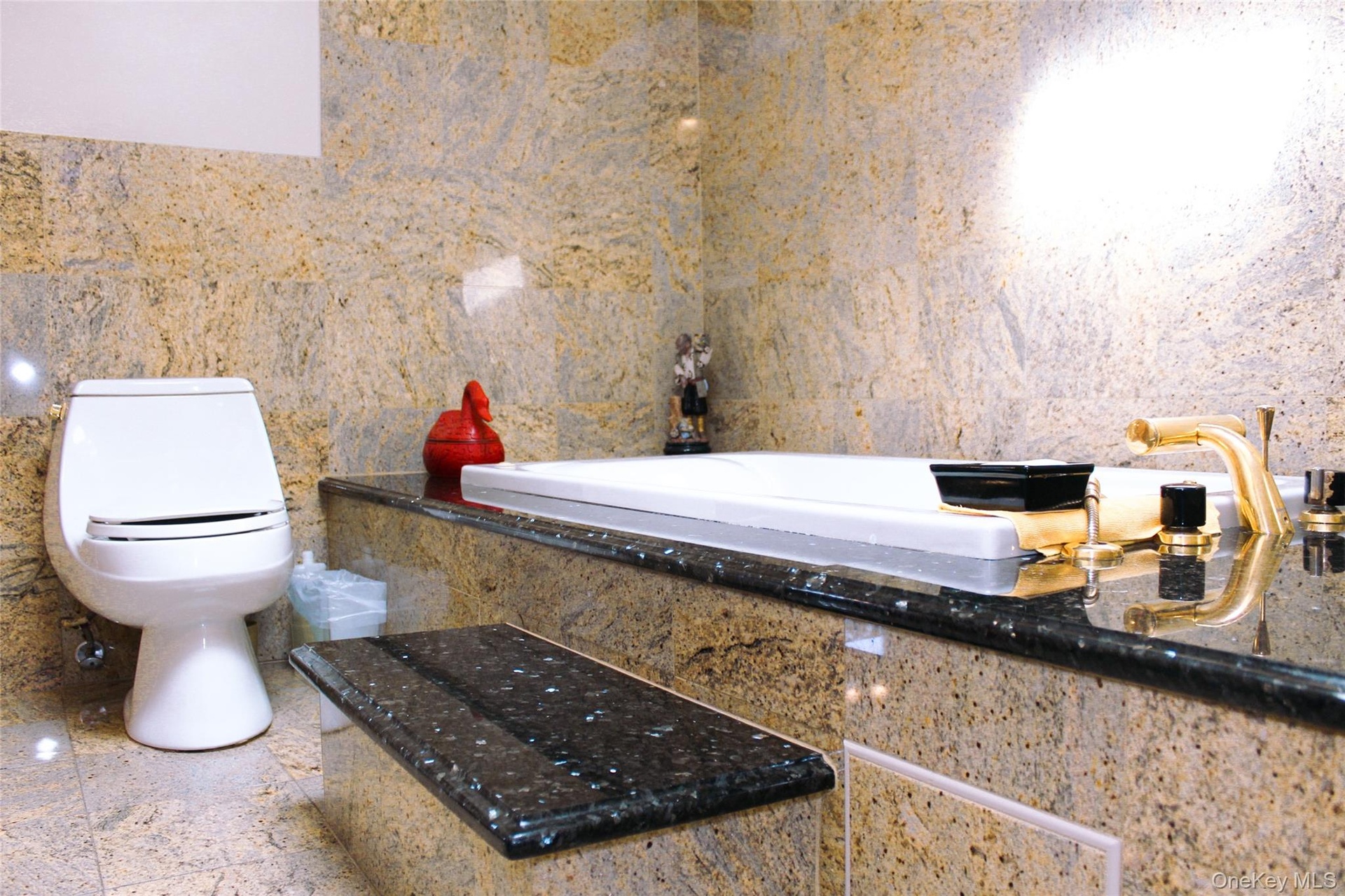 2nd floor bathroom has built-in soaking tub, tile flooring, wall-mounted oval mirror, wood cabinetry with polished hardware, and stone countertops