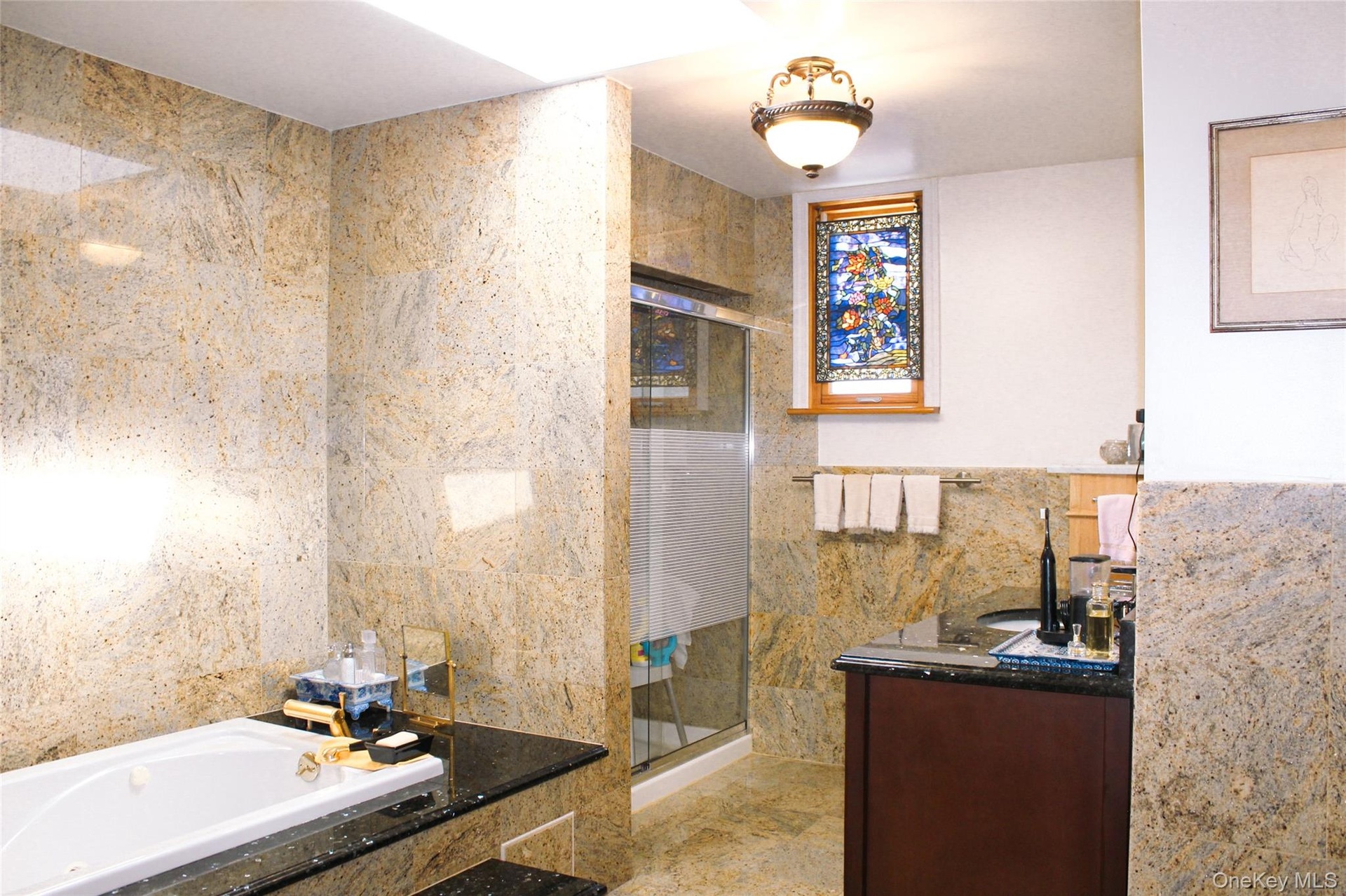 2nd floor bathroom has tiled walls and flooring, built-in bathtub, glass-enclosed shower, stained glass window, and vanity with dark countertop