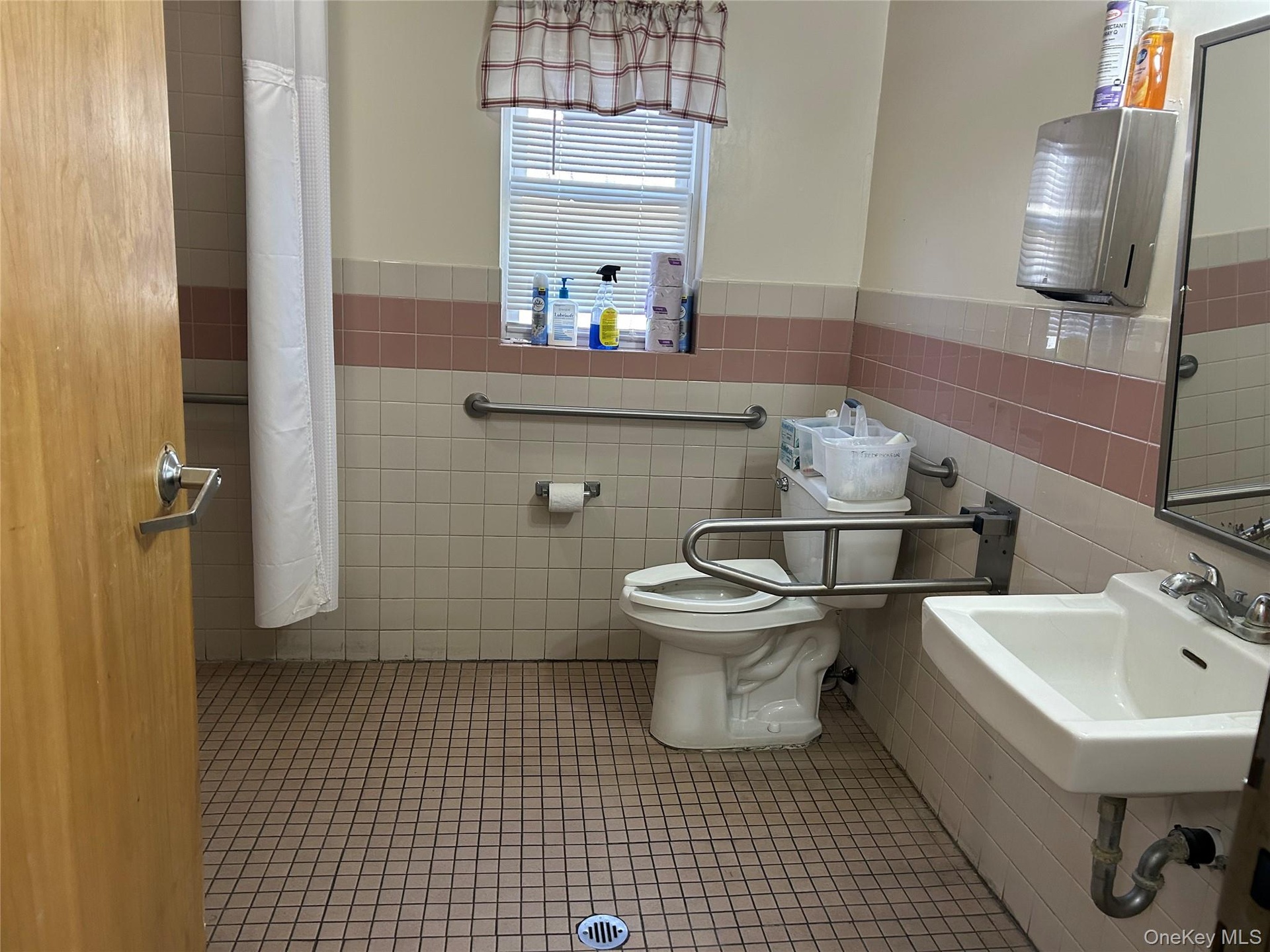Bathroom featuring tile patterned flooring, a wainscoted wall, and tile walls