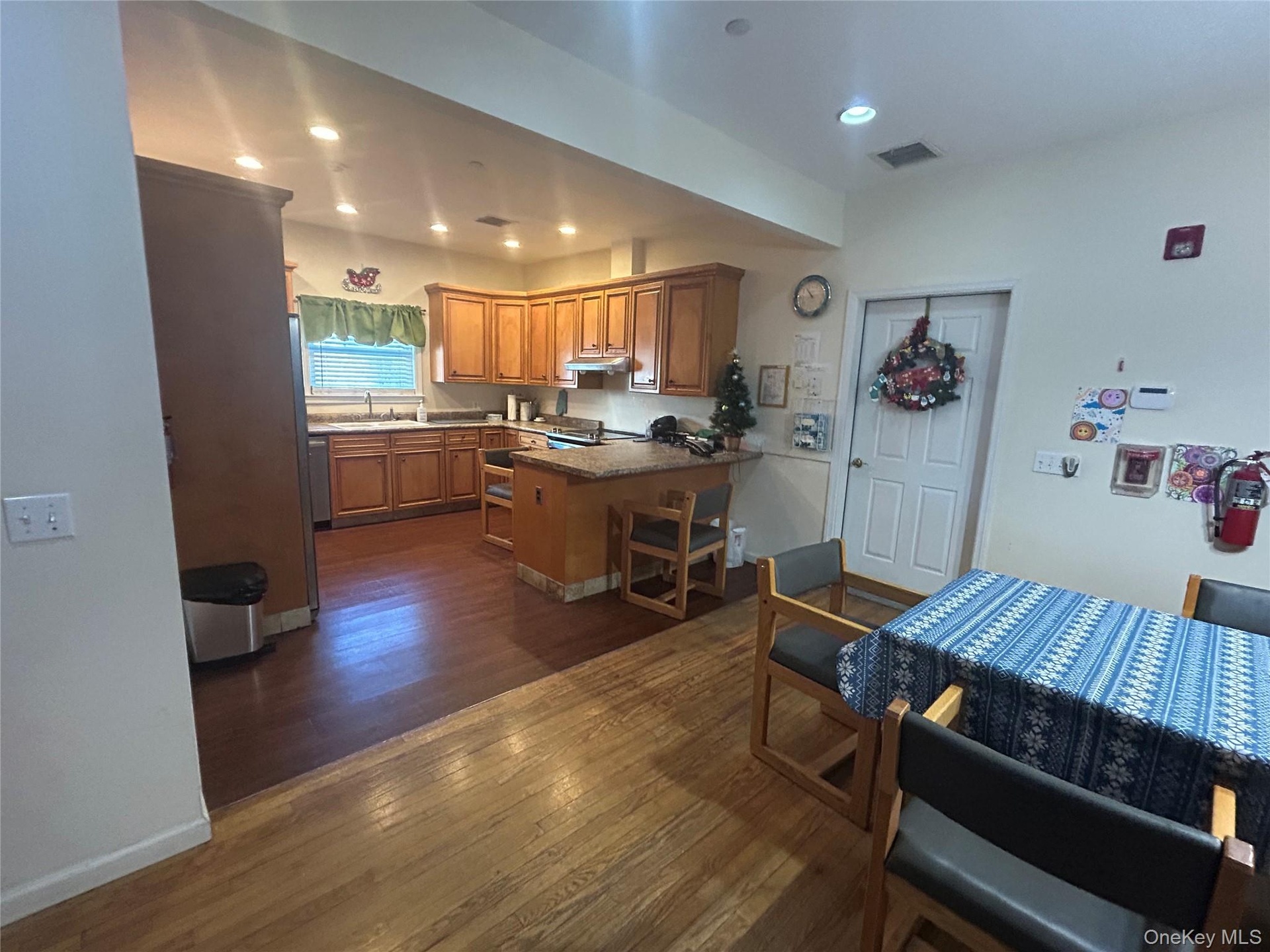 Kitchen with a peninsula, dark wood-style flooring, brown cabinets, recessed lighting, and a breakfast bar