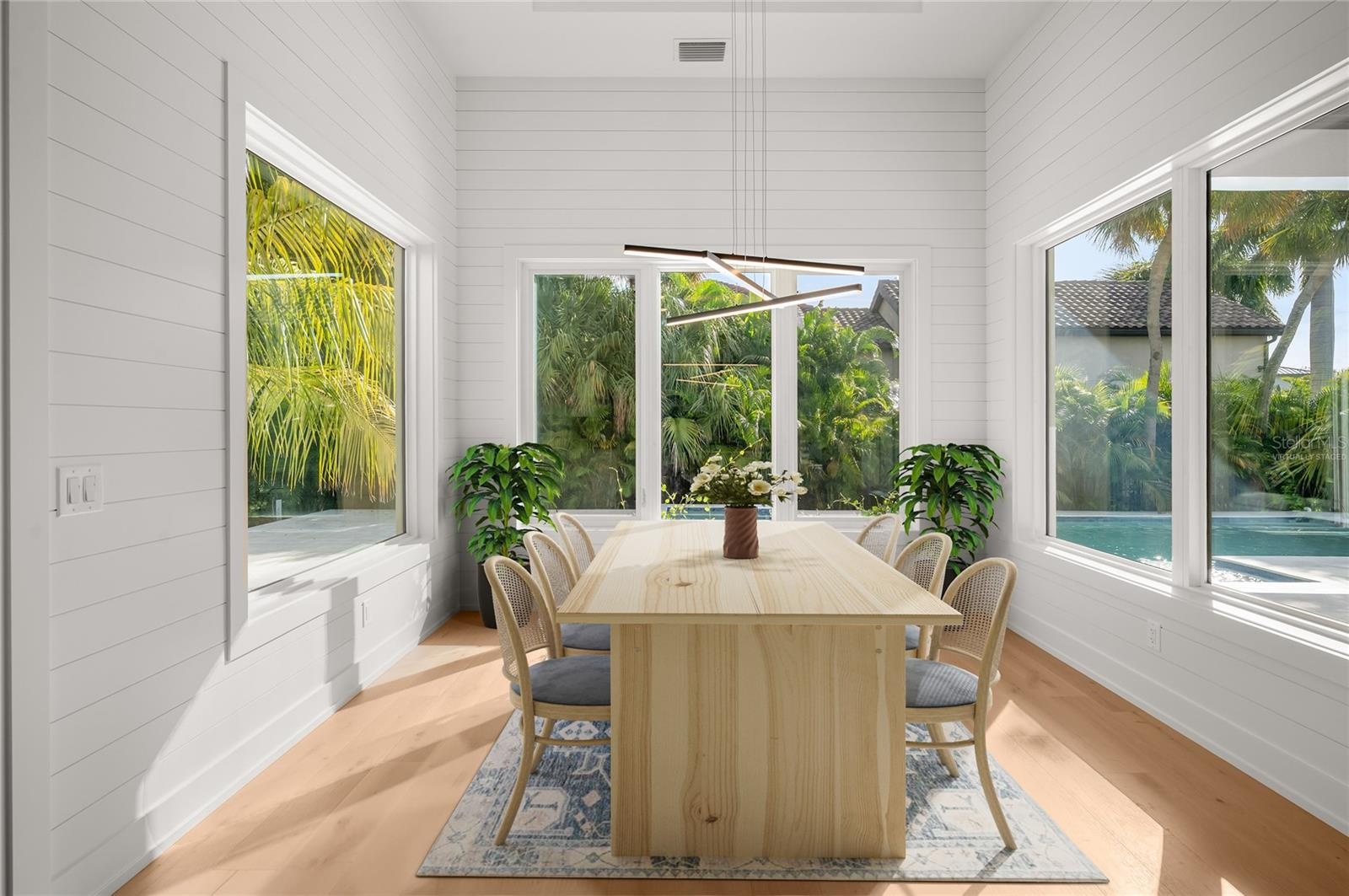 Virtually staged dining nook with elegant shiplap detailing, overlooking the private, beautifully landscaped backyard and pool.