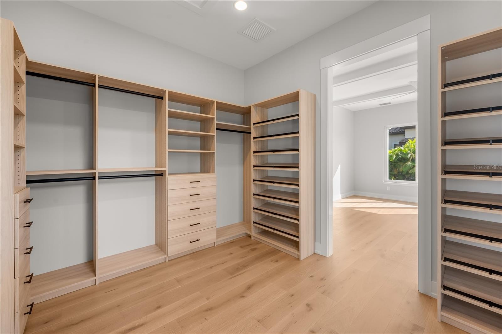 Primary bedroom walk in closet with built in closet system.