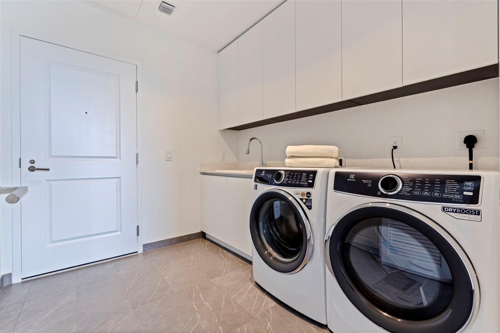 A dedicated laundry room with Electrolux washer and dryer, sink, and generous built-in storage.